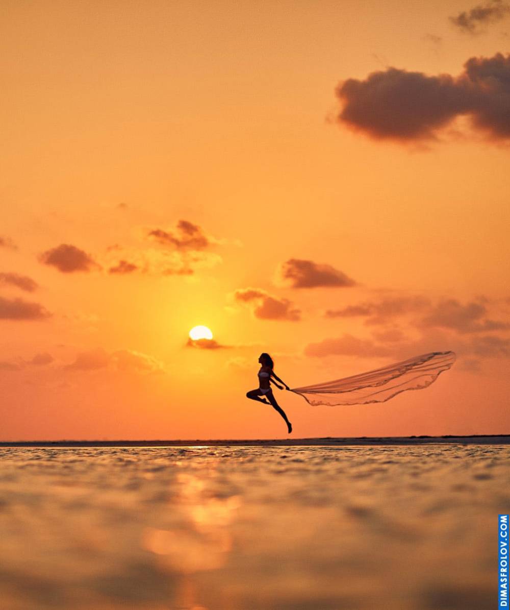 Creative beach photo at sunset with a woman jumping with a long veil
