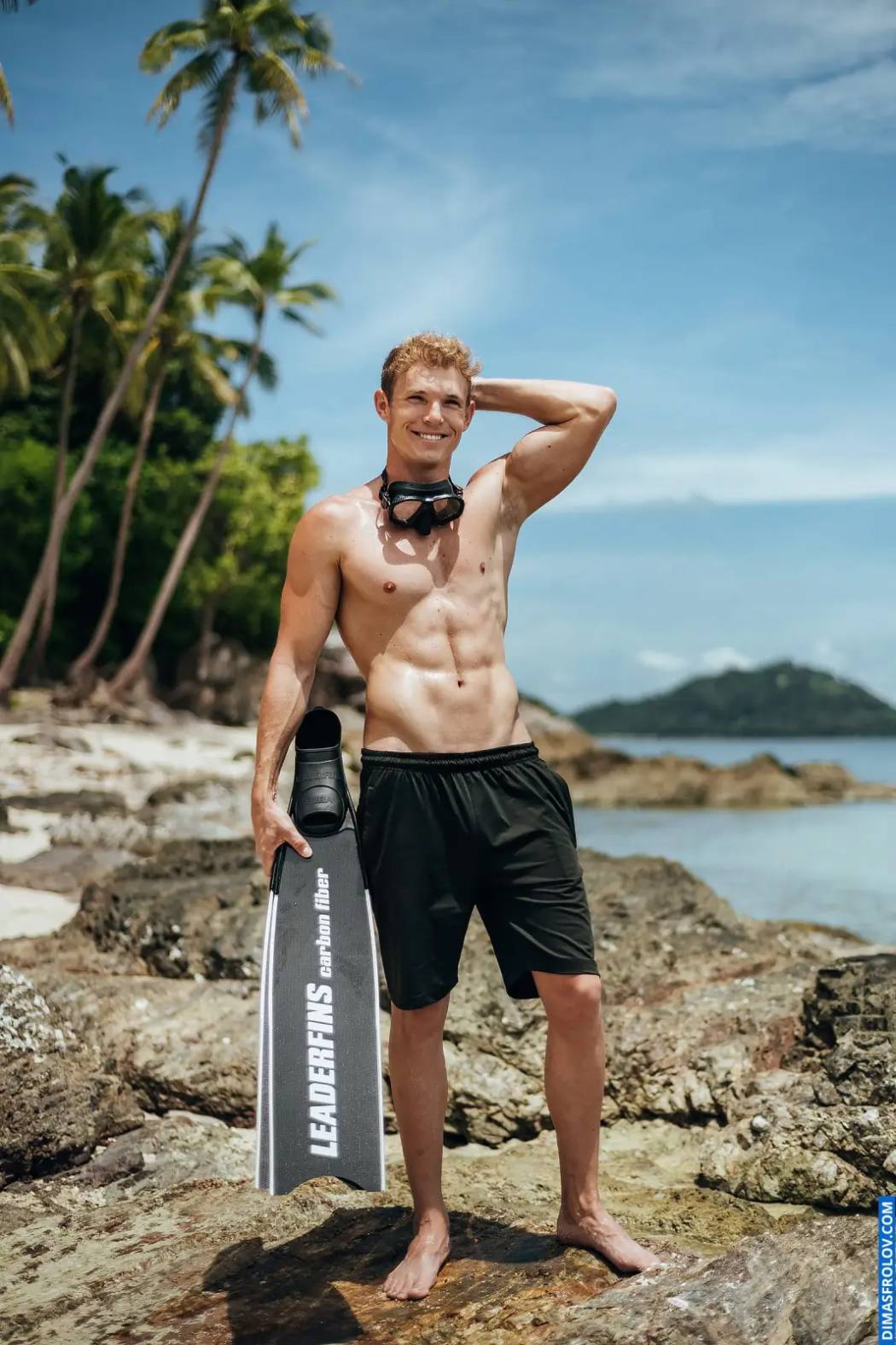 ภาพพอร์ตเทรตชายหุ่นดีบนชายหาด พร้อมอุปกรณ์ดำน้ำและกางเกงขาสั้นสีดำ