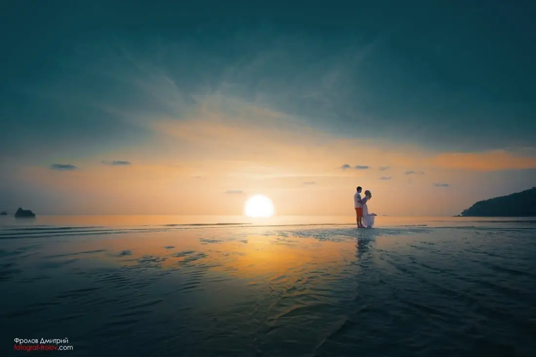 คู่รักกอดกันในน้ำตื้นท่ามกลางพระอาทิตย์ตก