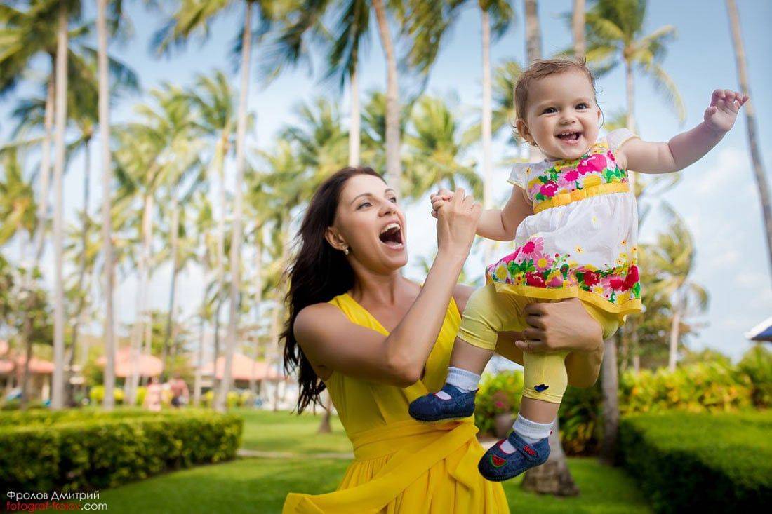 Cheerful moment — mom lifting daughter in a colorful dress, both smiling