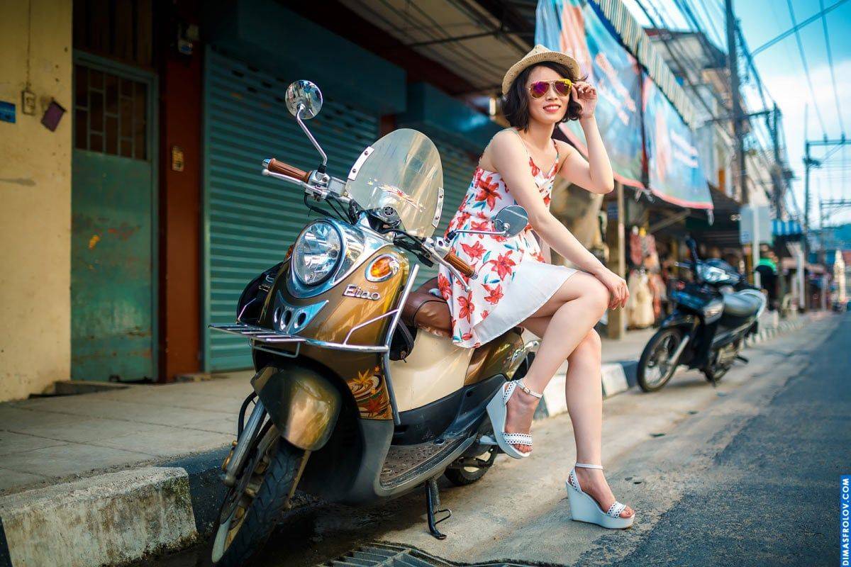 นักท่องเที่ยวสาวสุดสดใสในชุดหน้าร้อนถ่ายภาพกับสกู๊ตเตอร์บนถนนสีสันสดใส