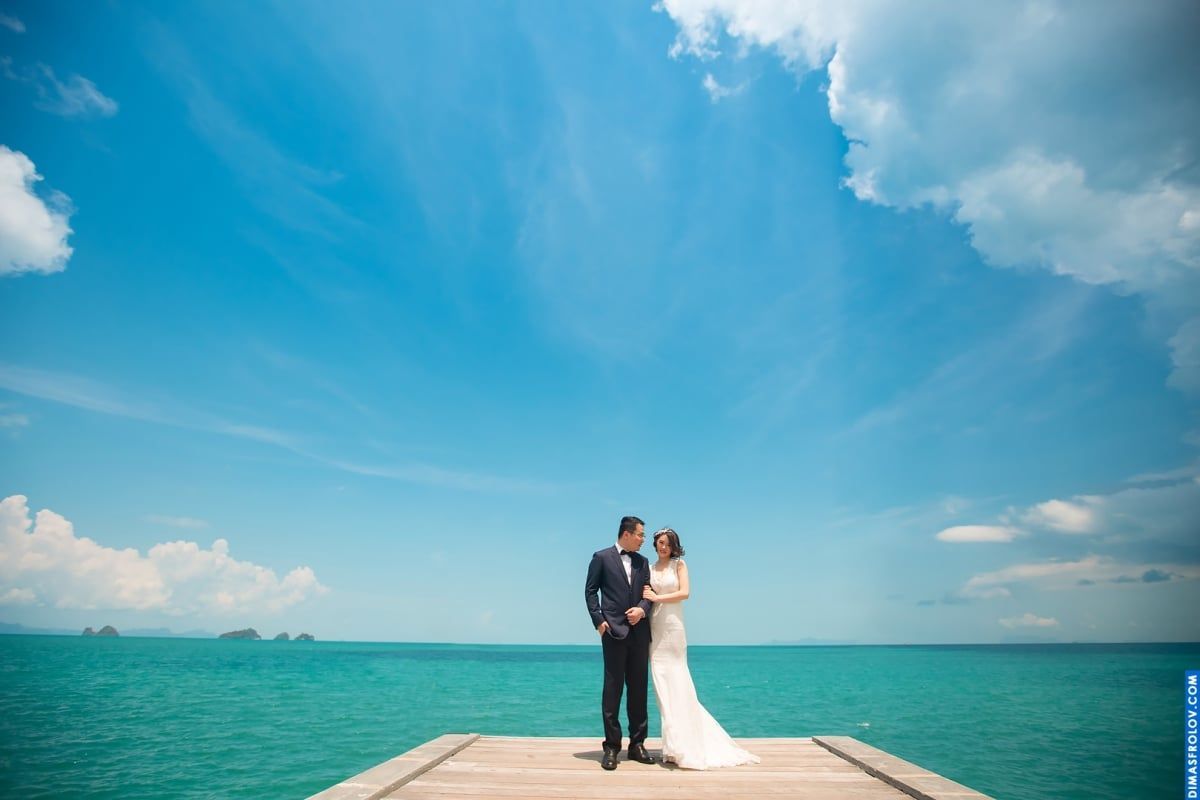 Bride and groom standing together on pier above the sea