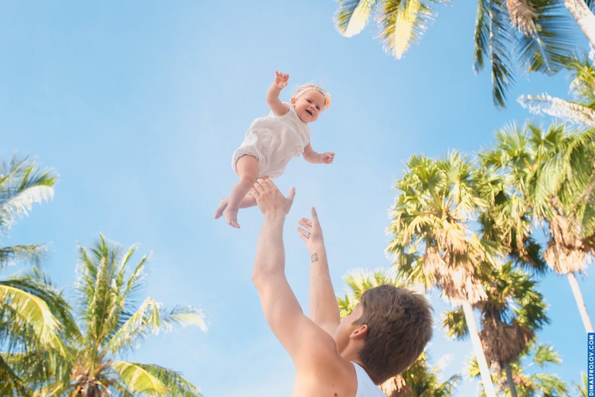 Sessão de fotos de bebê alegre — momento espontâneo do bebê voando com o céu tropical