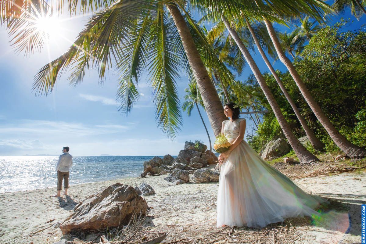 Bride standing by the palms with sunburst — peaceful and cinematic wedding moment
