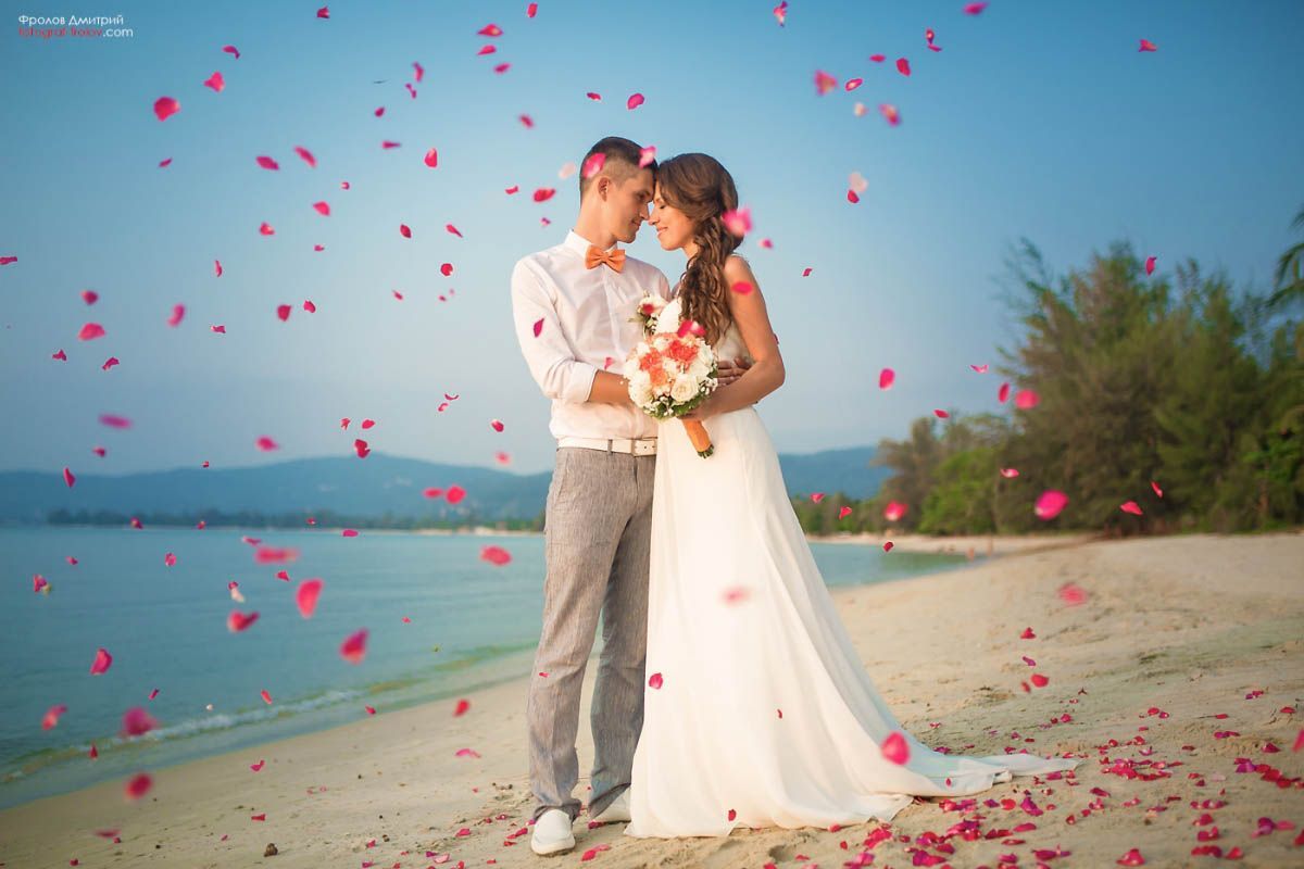 Petals in the air during beach wedding photoshoot — joyful celebration moment