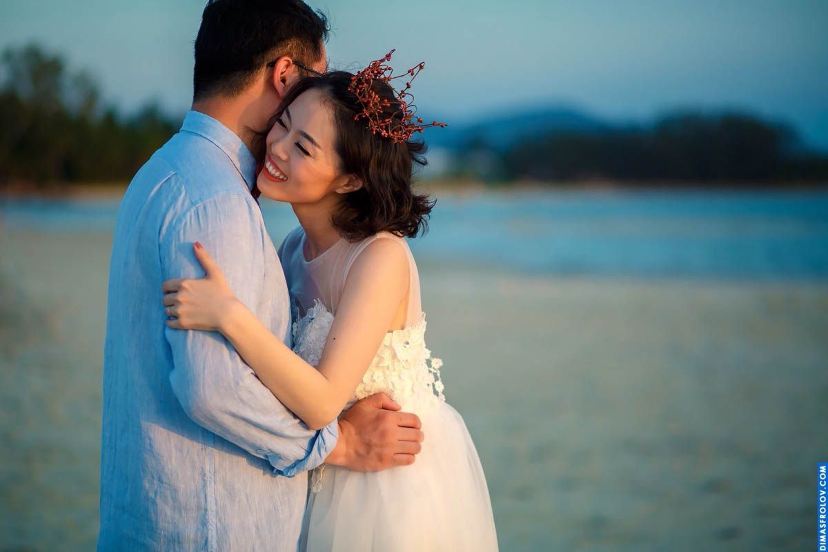 Tender beach moment during wedding shoot — bride in floral crown