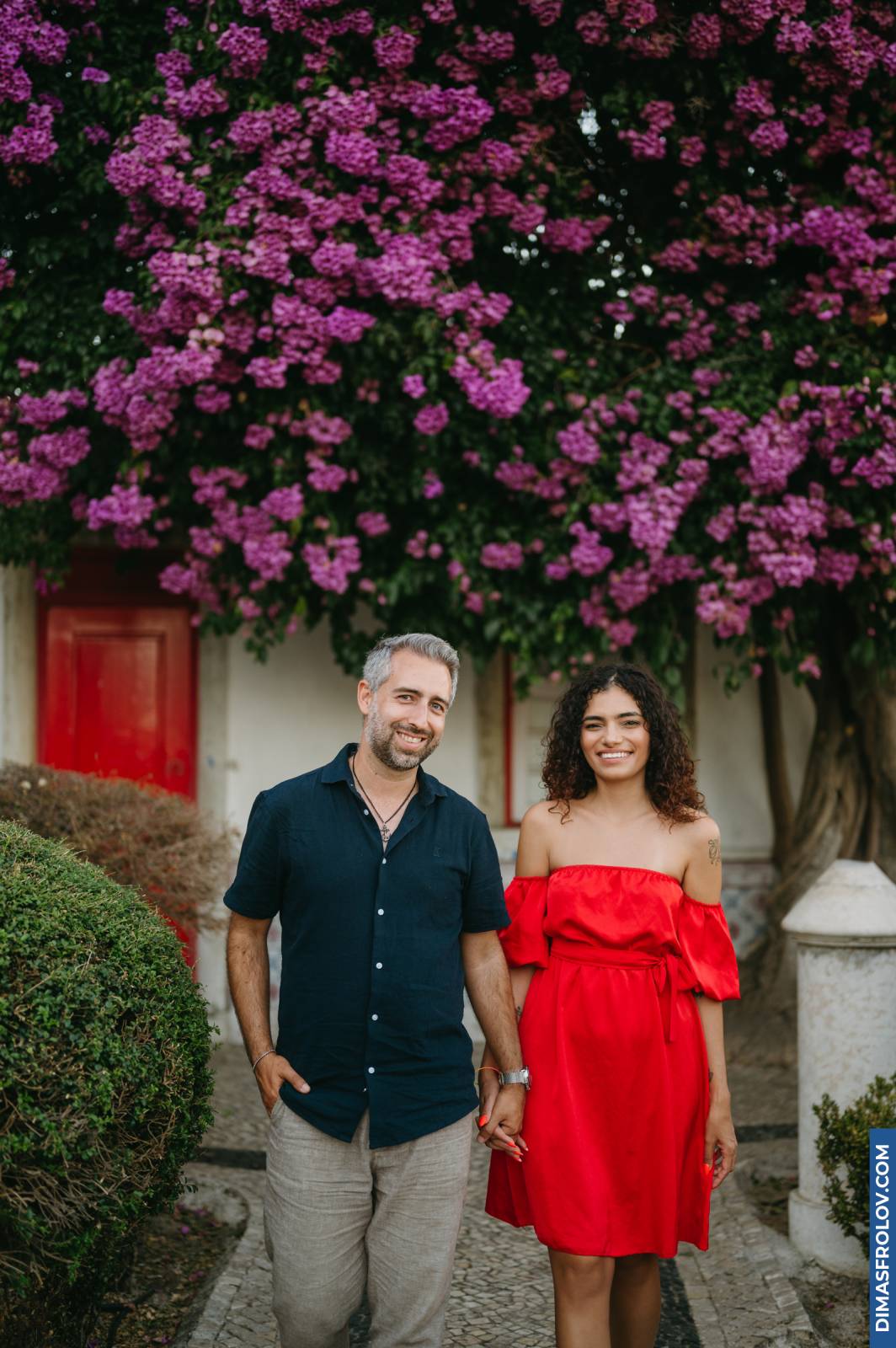 Couple holding hands under blooming bougainvillea in Lisbon