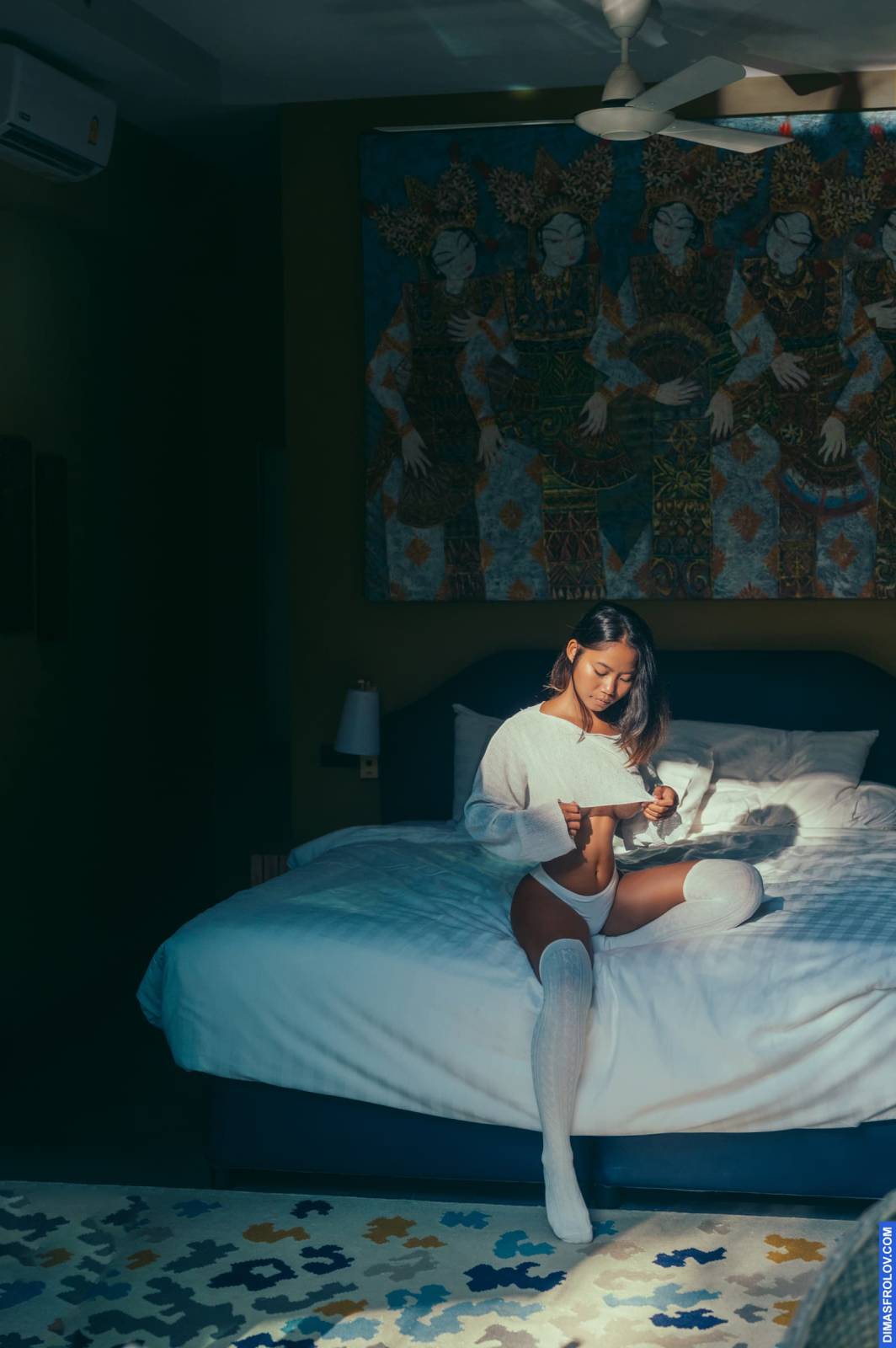 Retrato aconchegante de mulher em suéter e meias lendo na cama