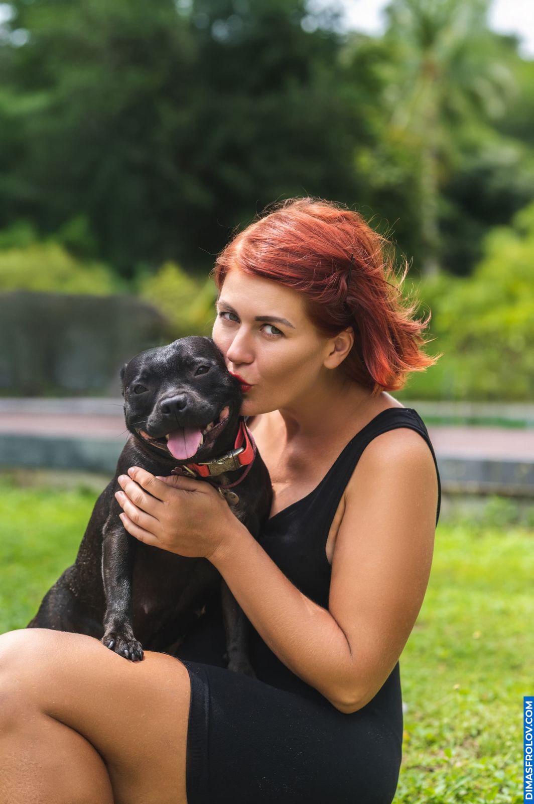 Joyful woman hugging her smiling staffy during outdoor dog photo shoot