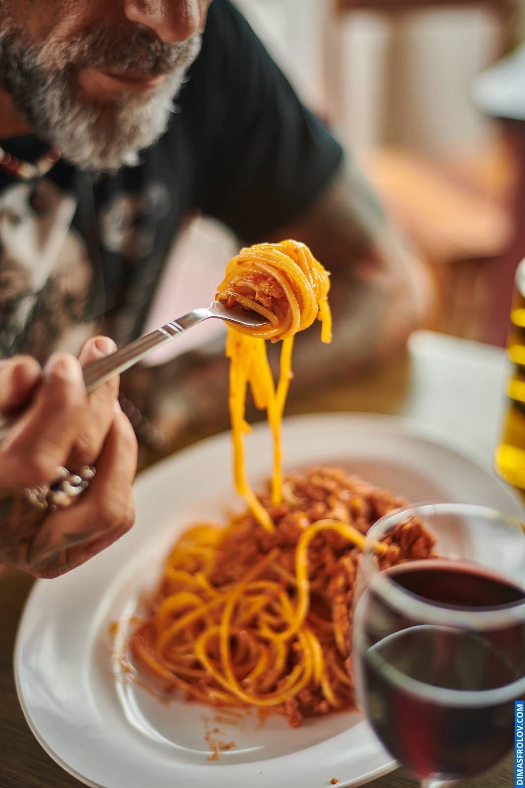 Foto de comida estilo de vida em luz natural, apresentando uma pessoa comendo espaguete com um garfo, capturando um momento real de refeição para entusiastas da gastronomia e blogueiros.