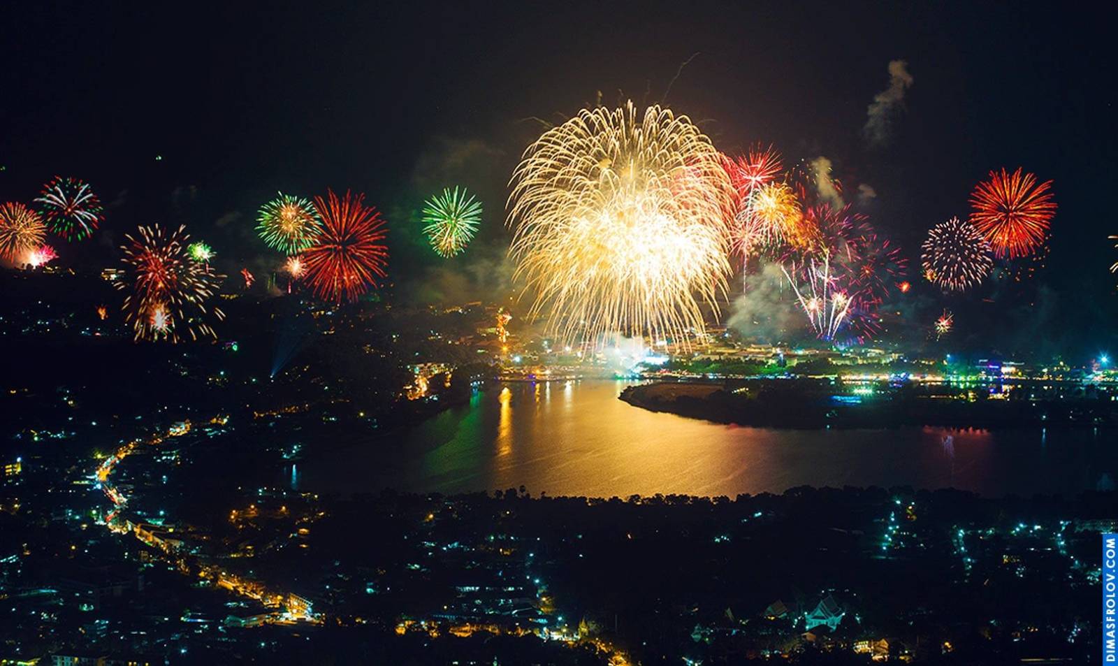 Vibrant fireworks display over a city at night, with colorful bursts illuminating the dark sky and reflecting on a body of water