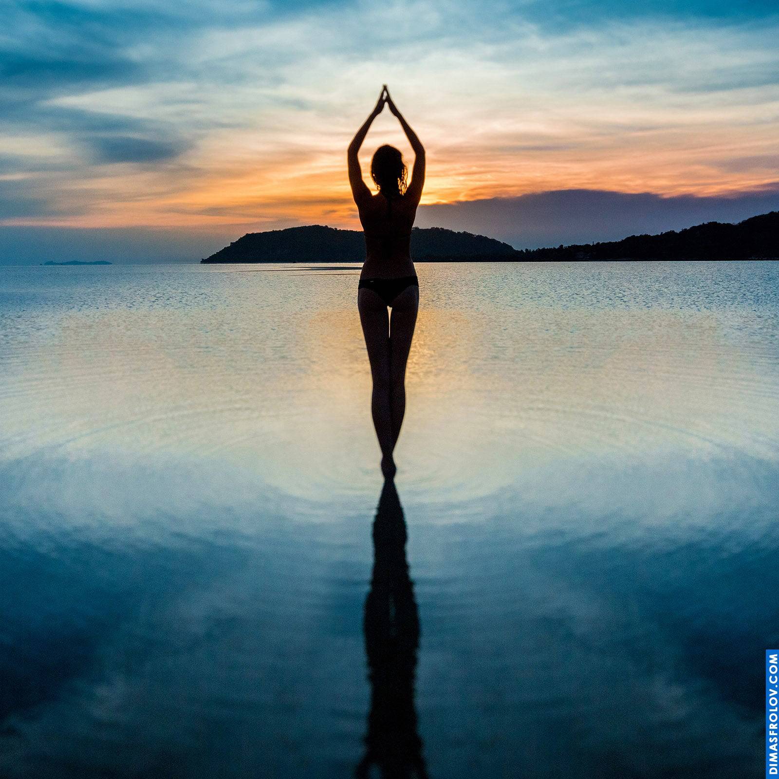Silhouette of a woman standing in the water during sunset meditation