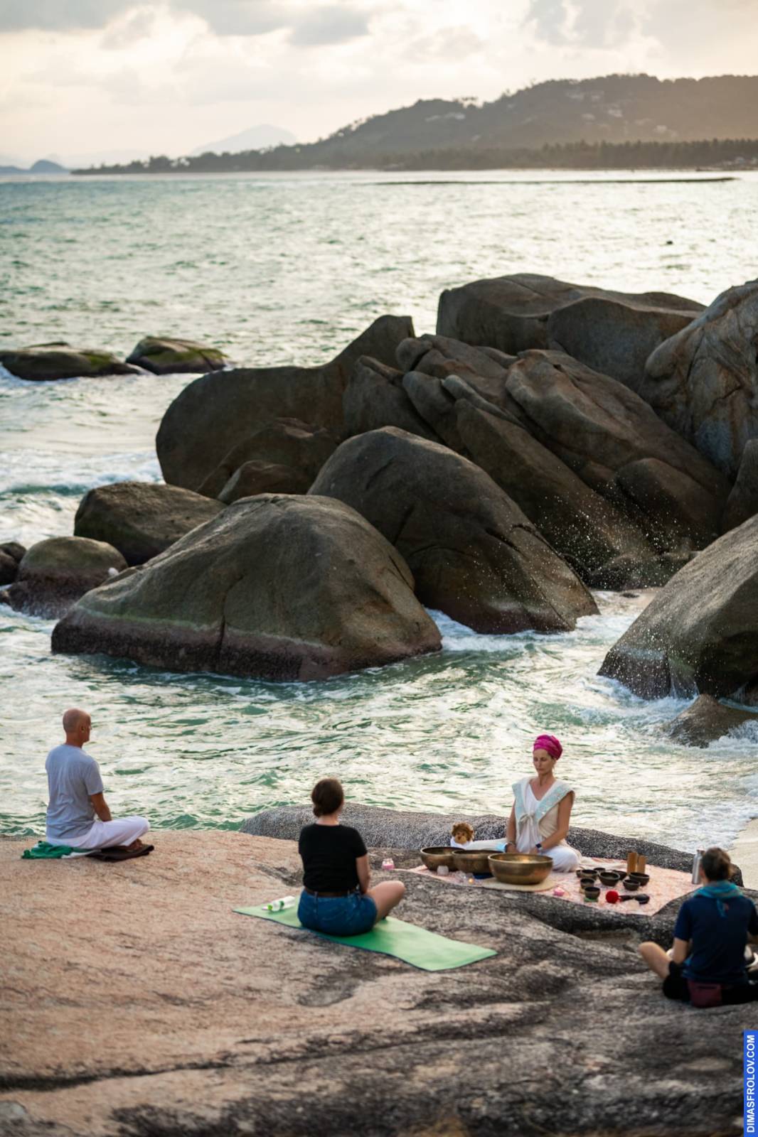 Yoga and sound healing workshop on the rocks by the sea at sunrise