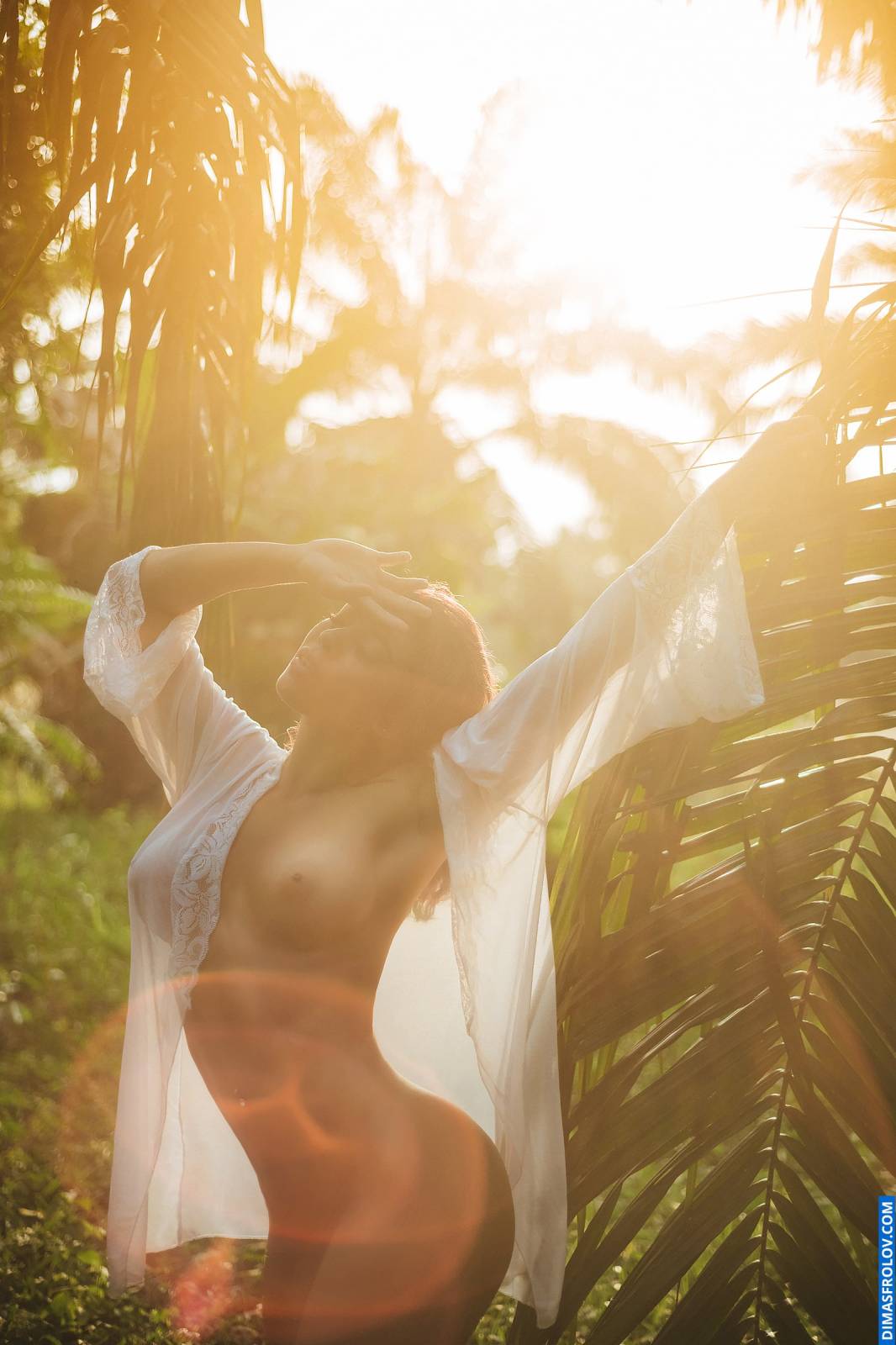 Foto de boudoir ao ar livre, contraluz, de mulher sem blusa em jardim tropical