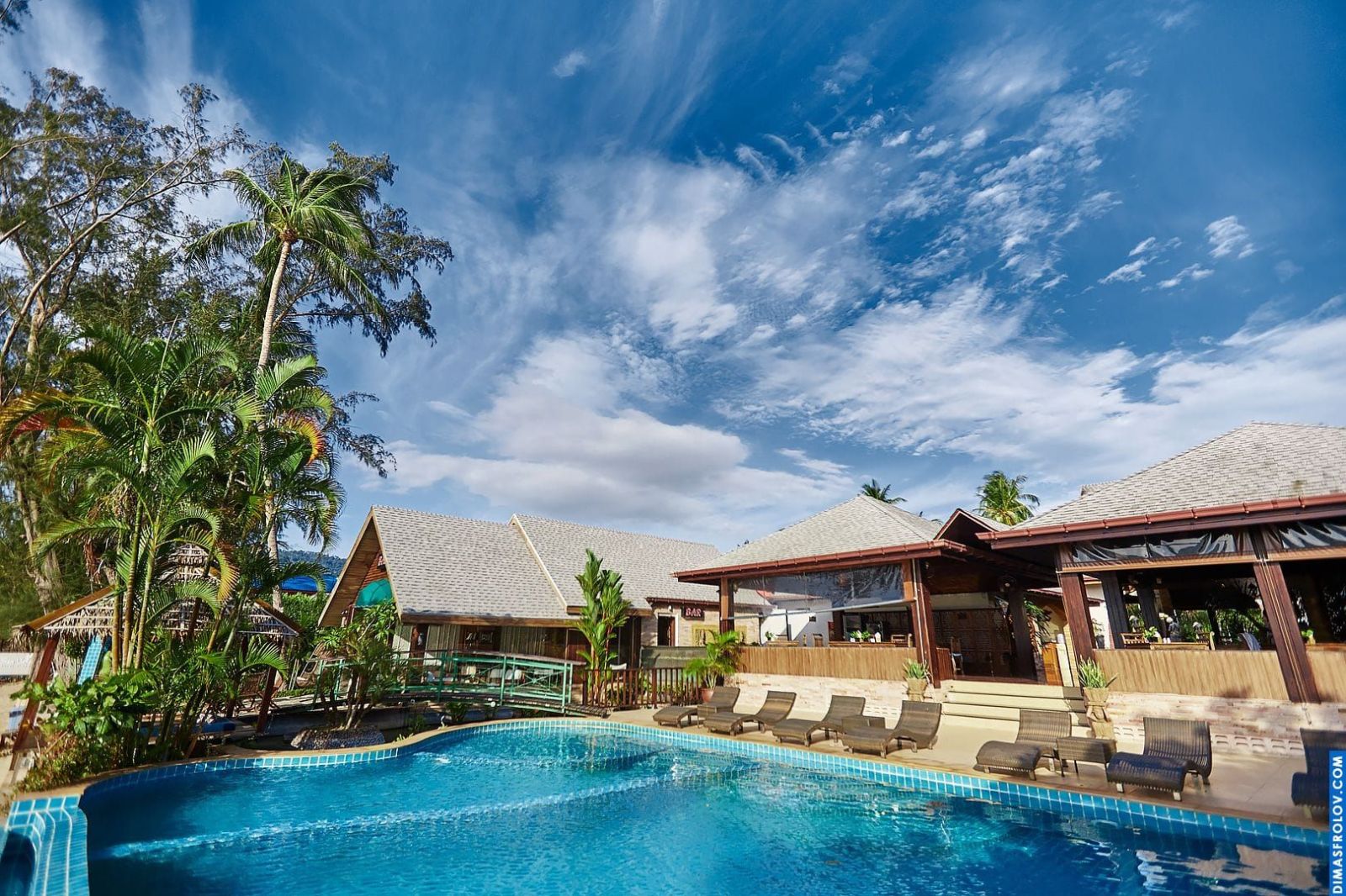 Tropical resort at dusk: illuminated villas and pool reflecting the twilight sky