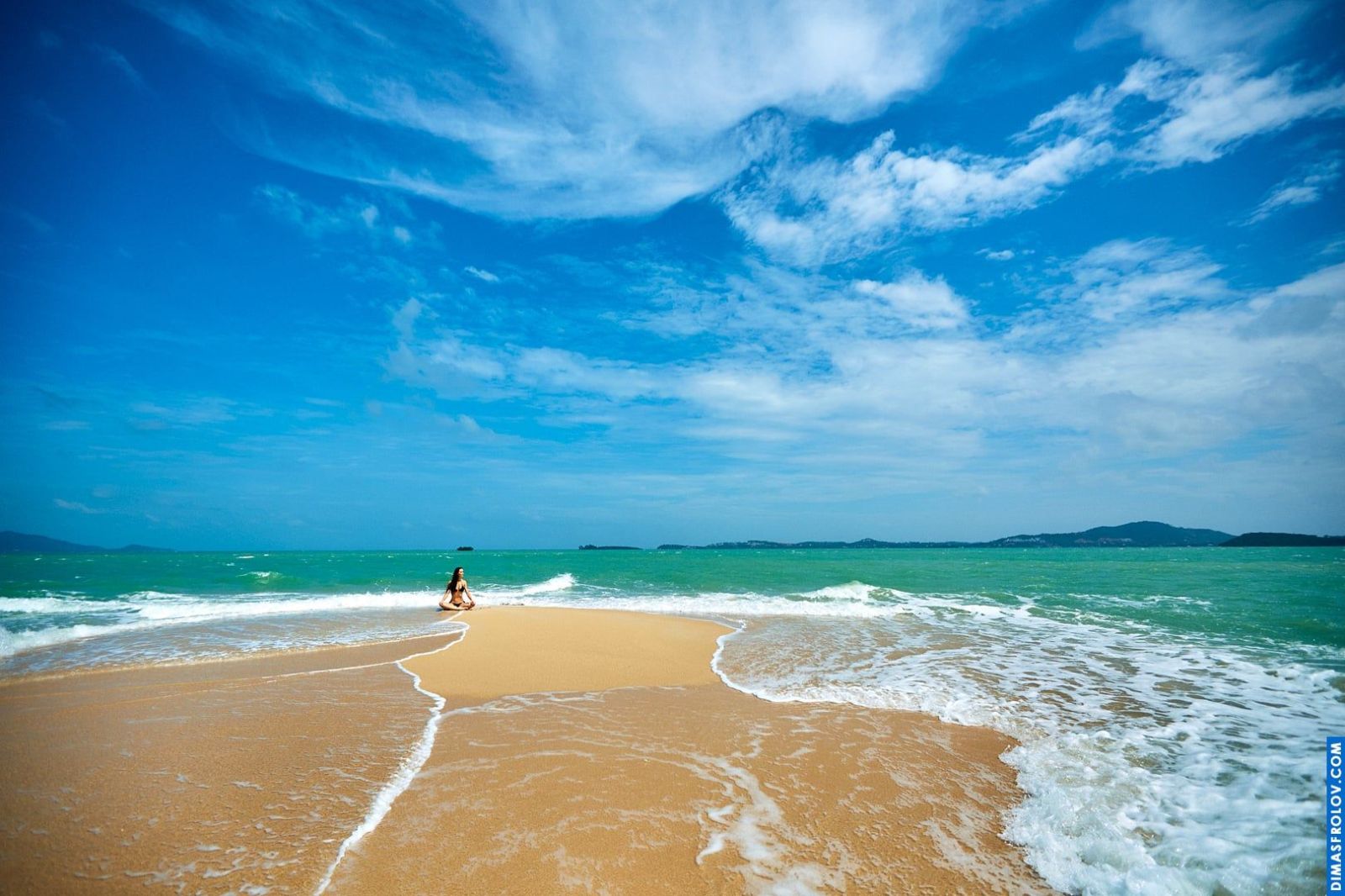 Wide-angle beach landscape with a single woman walking into the ocean
