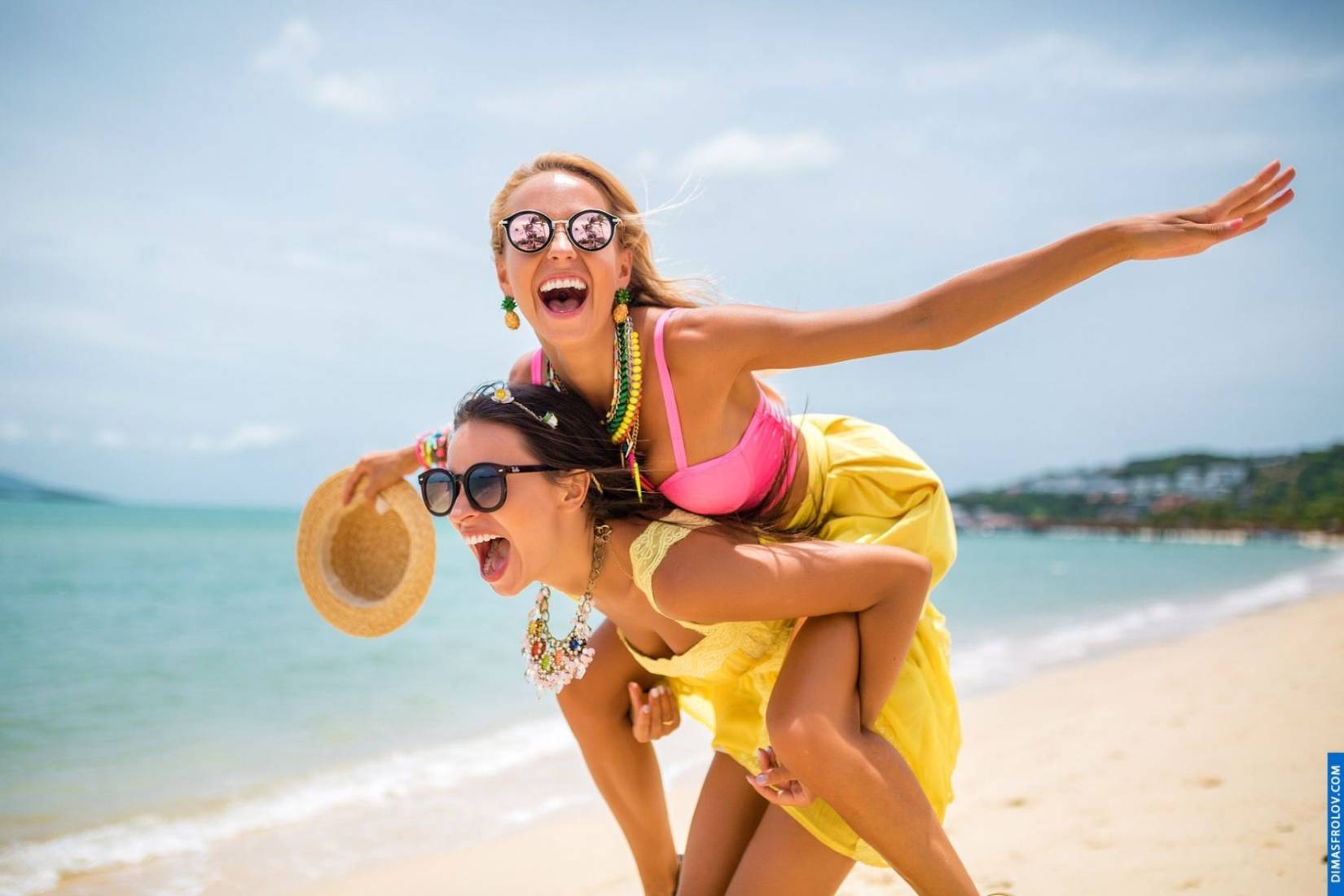 ภาพไลฟ์สไตล์ริมชายหาดของเพื่อนสองคนในชุดเดรสสีเหลืองหัวเราะอย่างสนุก