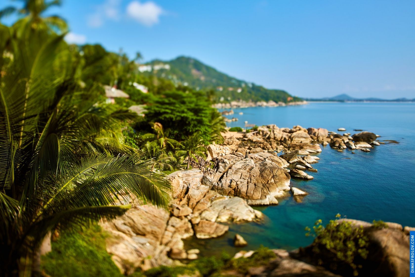 Picturesque view of a coastal town nestled among lush green hills and overlooking a clear blue bay
