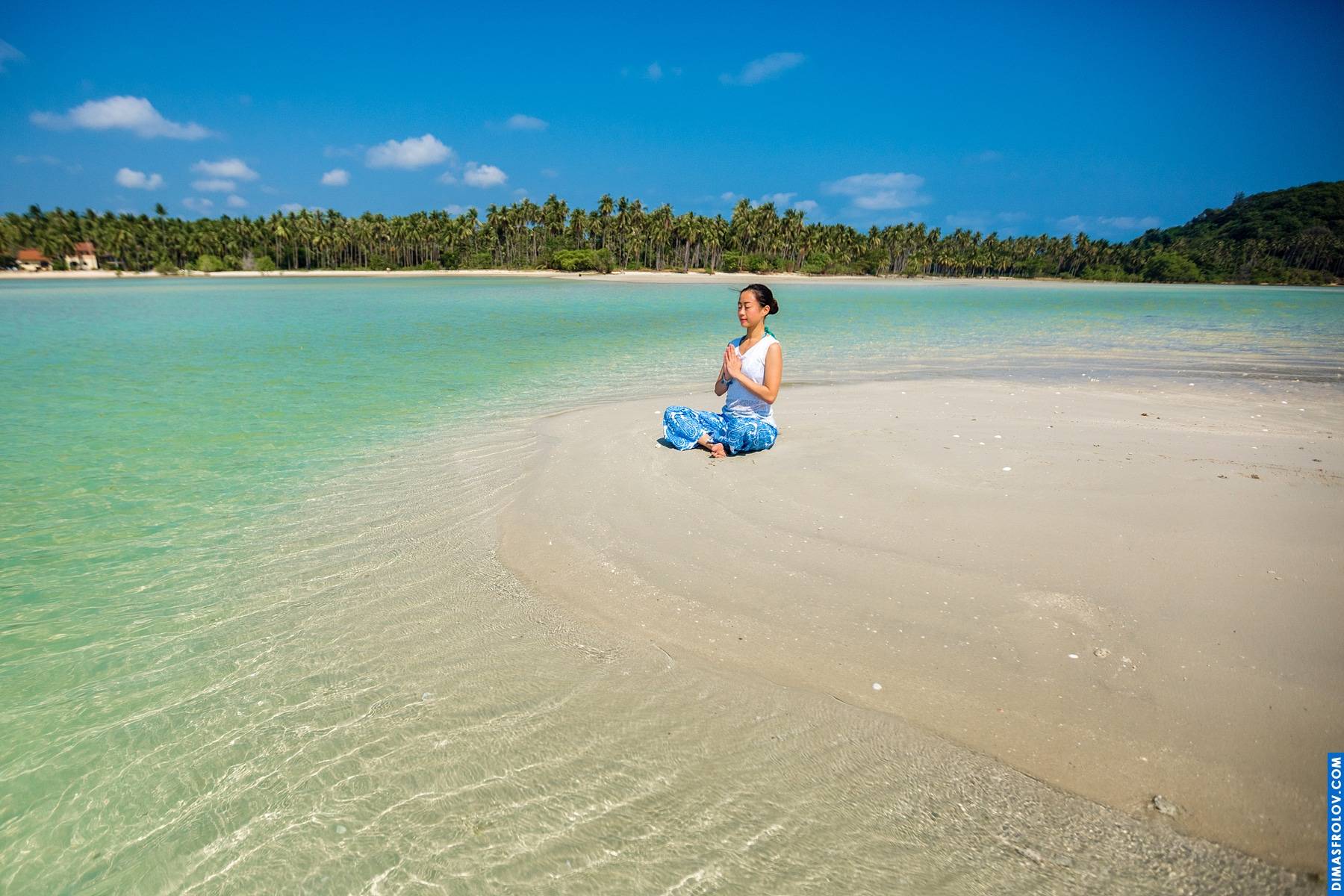 ชายหาดเขตร้อนที่มีน้ำทะเลสีเทอร์ควอยซ์ใสและคนที่ยืนอยู่ในระยะไกล เพลิดเพลินกับทิวทัศน์อันเงียบสงบ