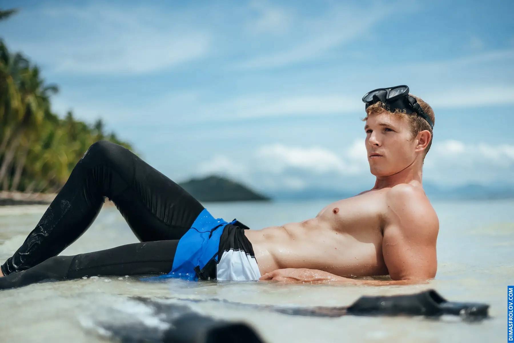 Relaxed beach portrait of man in diving gear resting on shoreline
