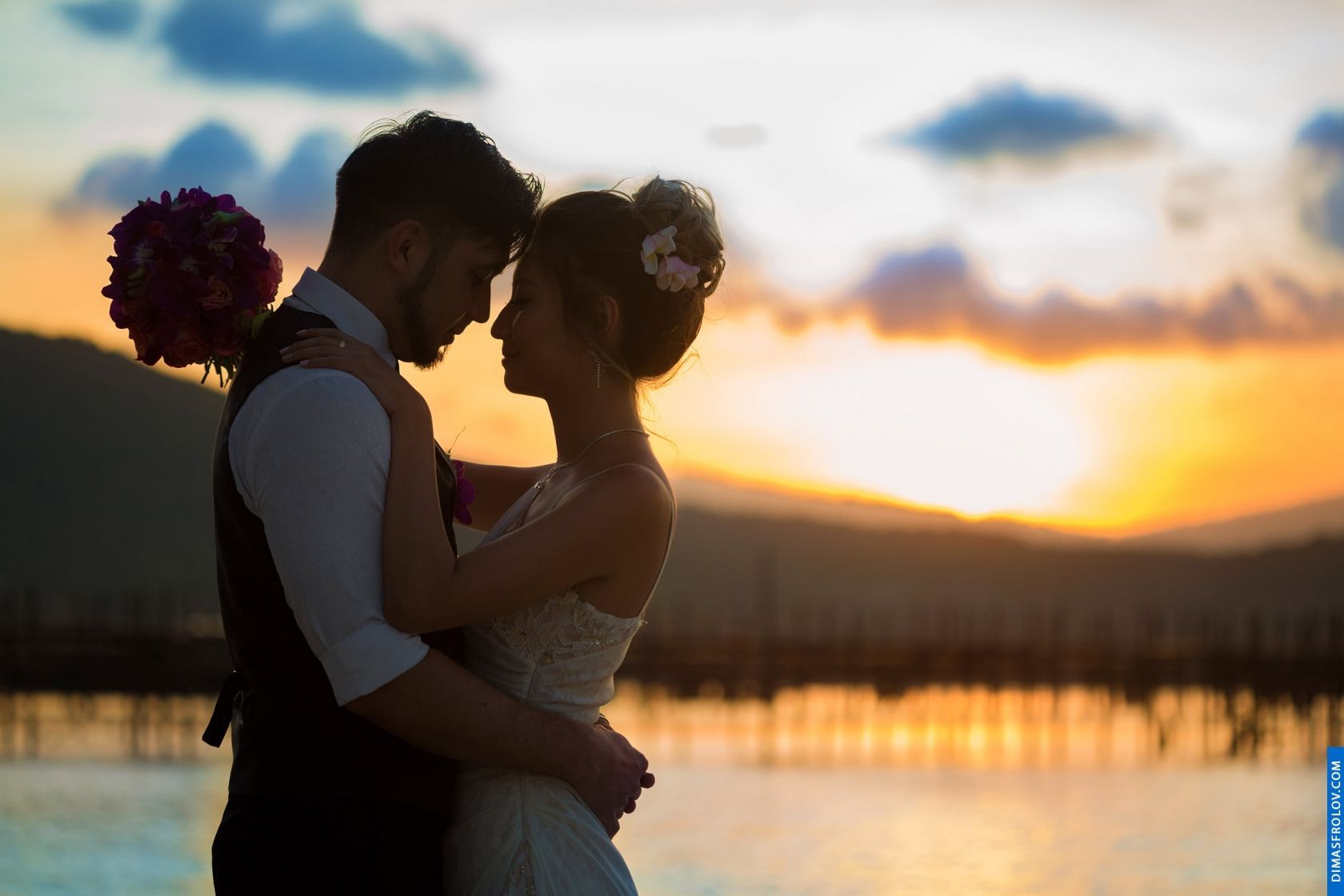 Romantic wedding couple at sunset on the lake shore in golden light