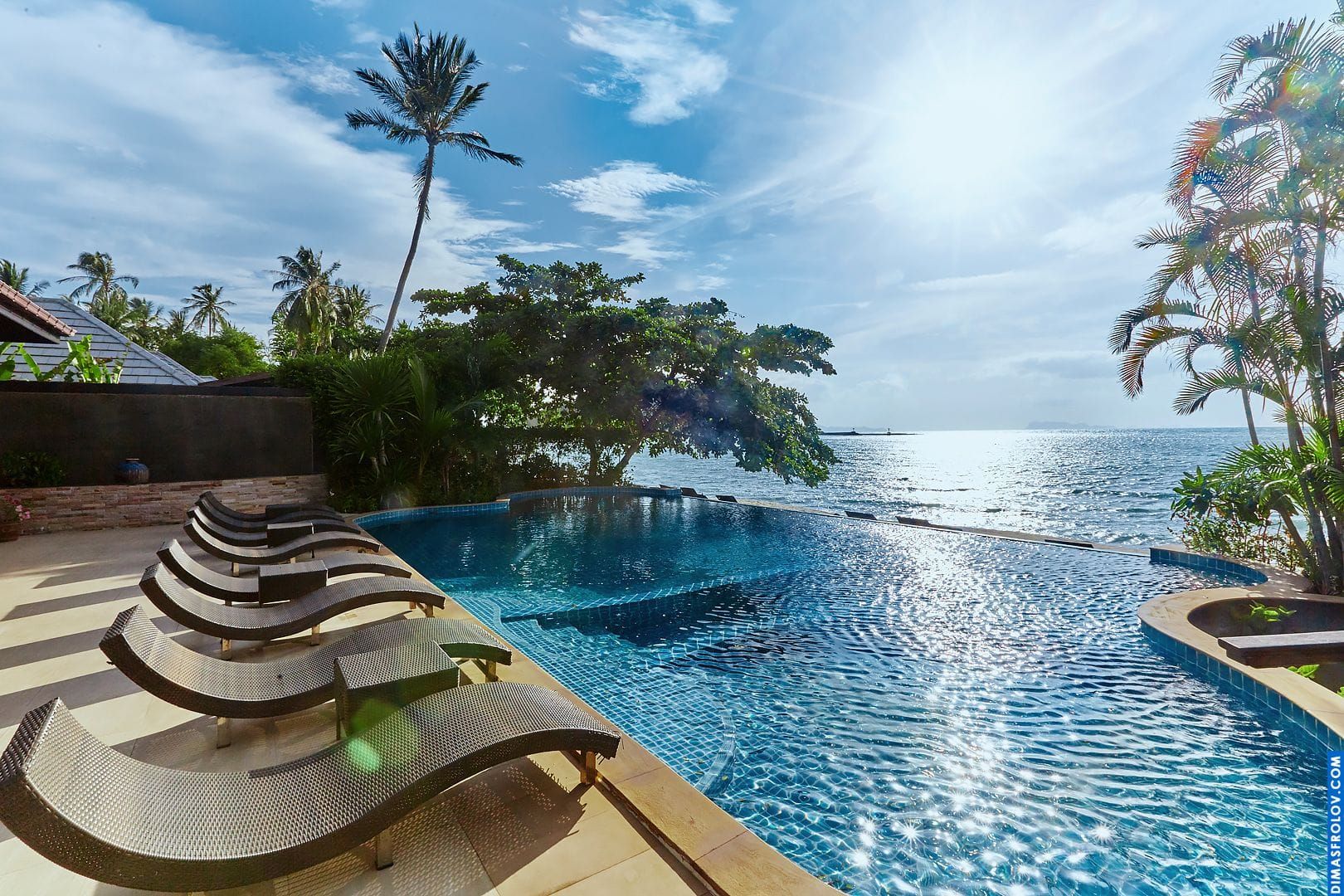 Luxury pool deck: comfortable sun loungers by a serene infinity pool overlooking the ocean