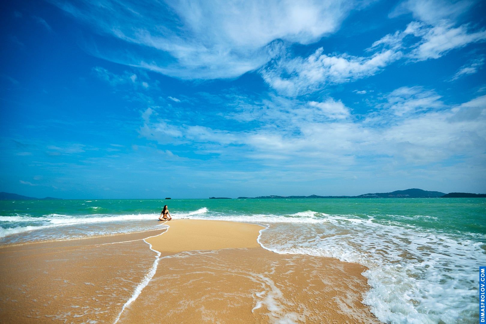 Wide-angle beach landscape with a single woman walking into the ocean