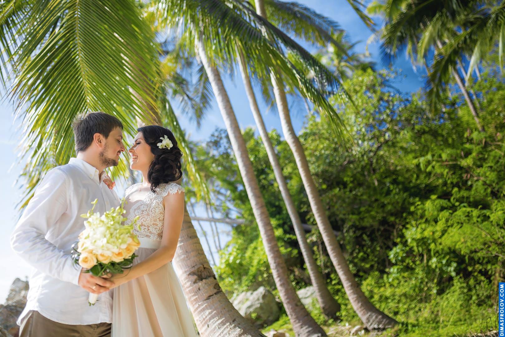 Bride and groom under palm trees — tropical love in natural sunlight