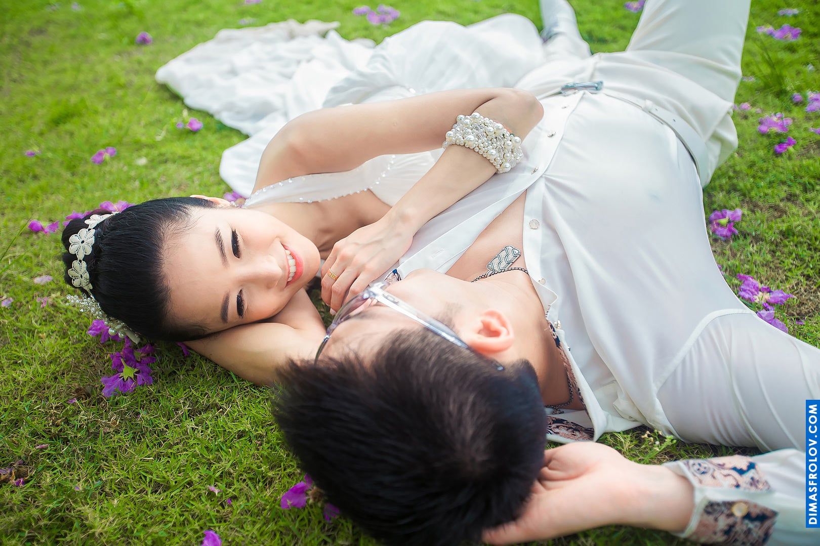 Wedding couple lying in the grass — intimate, relaxed and playful moment