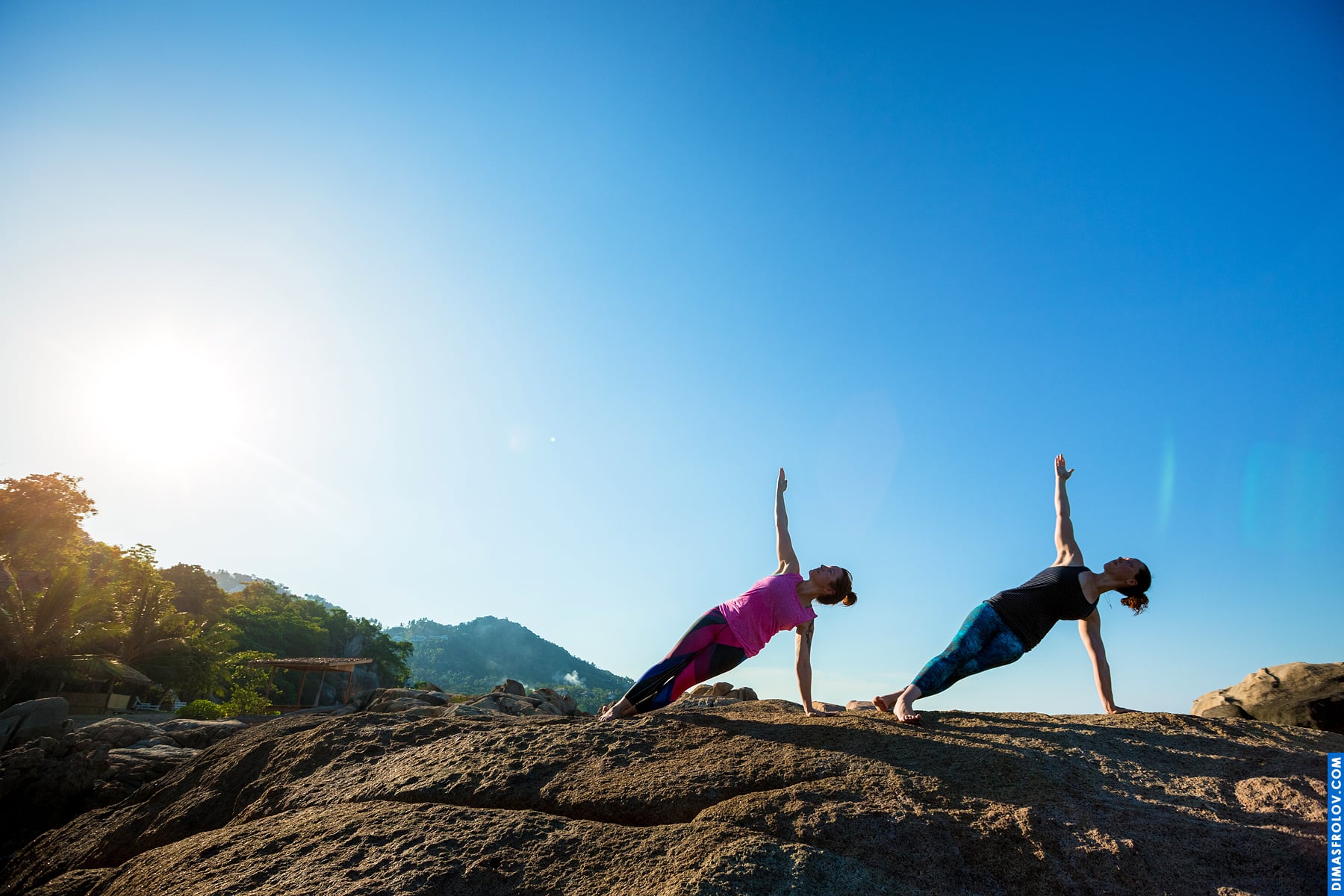 Sunrise yoga serenity: silhouette of two people in a balancing pose on rocks