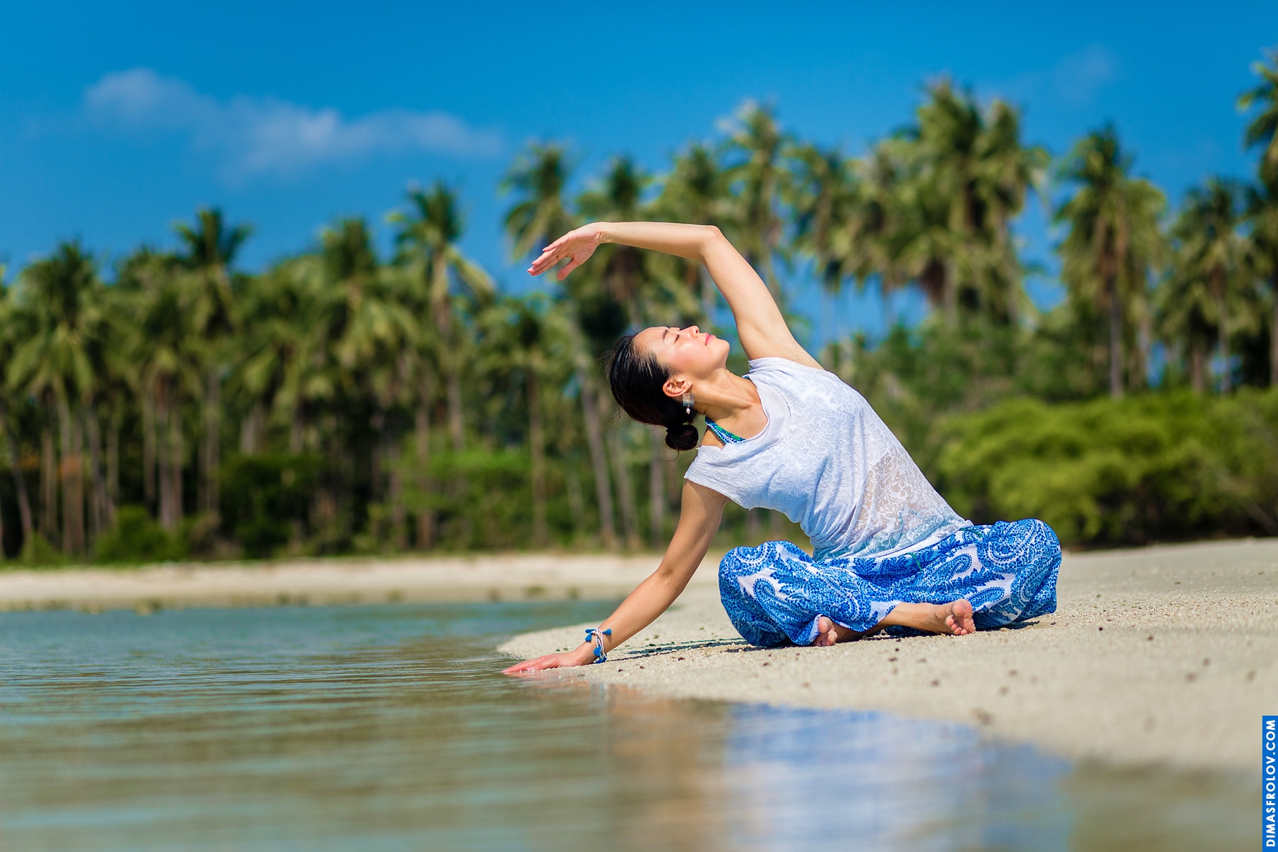 Dynamic beach yoga: woman in a twisting seated pose on the sand