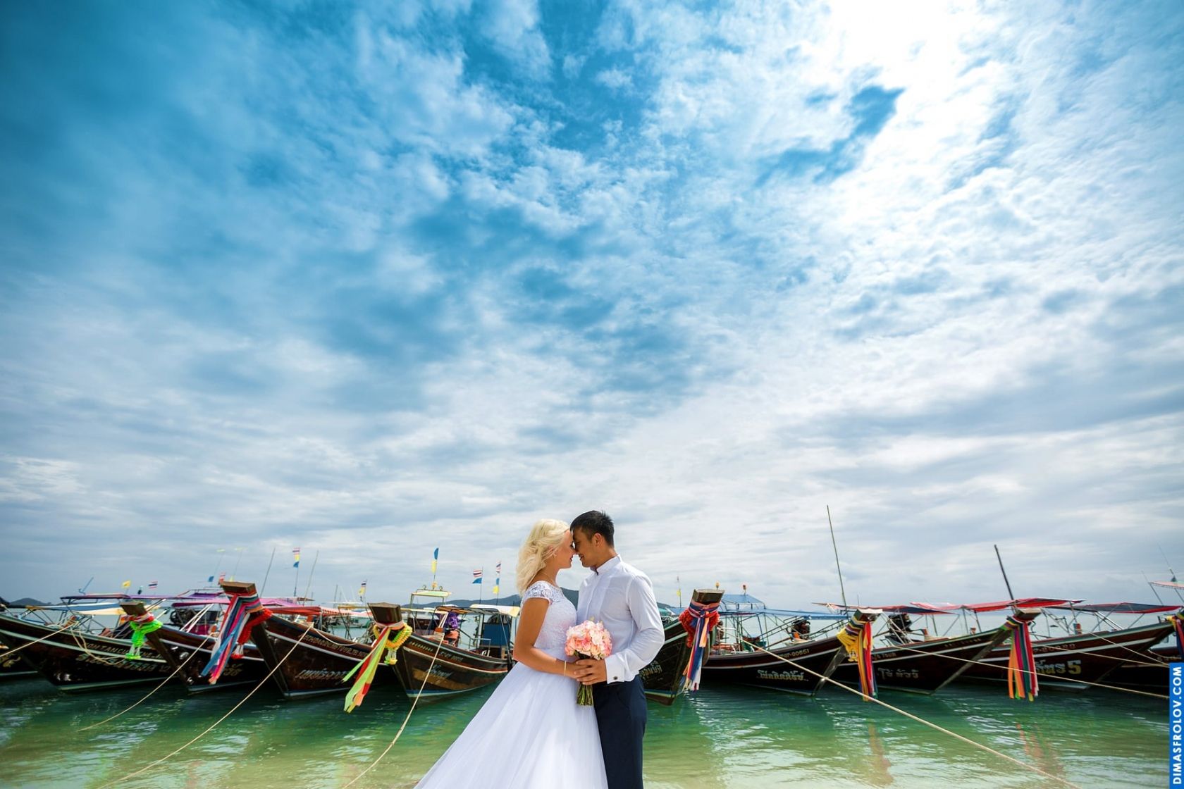 Wedding couple by traditional longtail boats — colorful and exotic destination vibe
