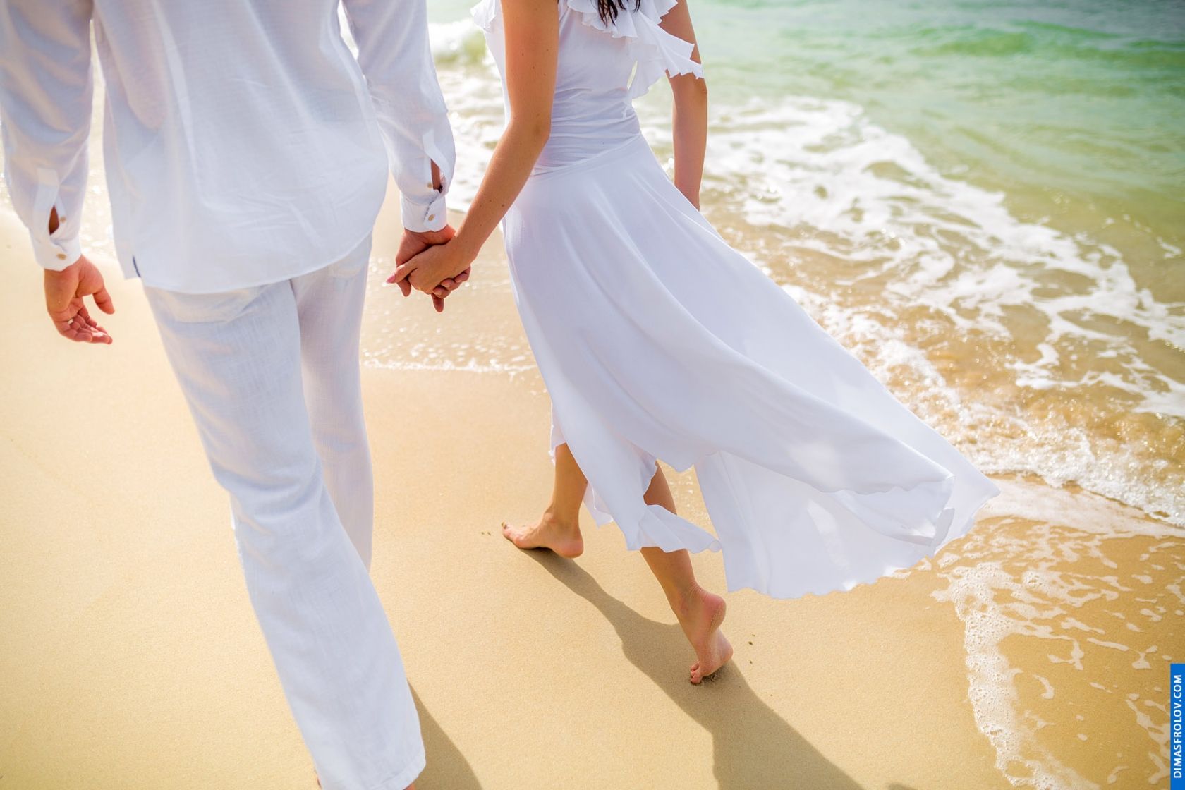 Close-up photo of couple walking barefoot along the shoreline