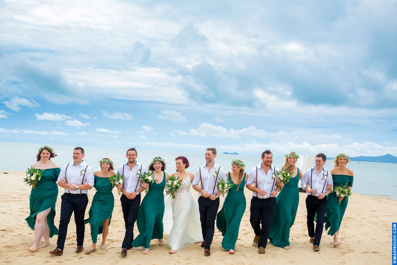 Wedding party walking on the beach — joyful group portrait with ocean backdrop