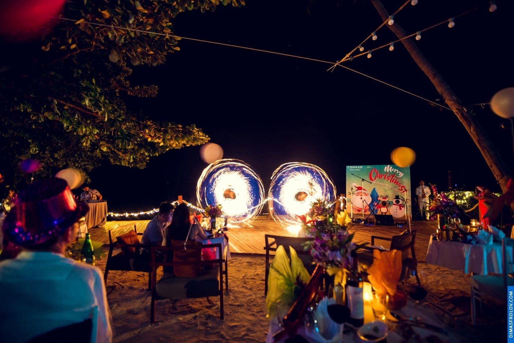 Nighttime event with fire dancers performing in front of audience on the beach