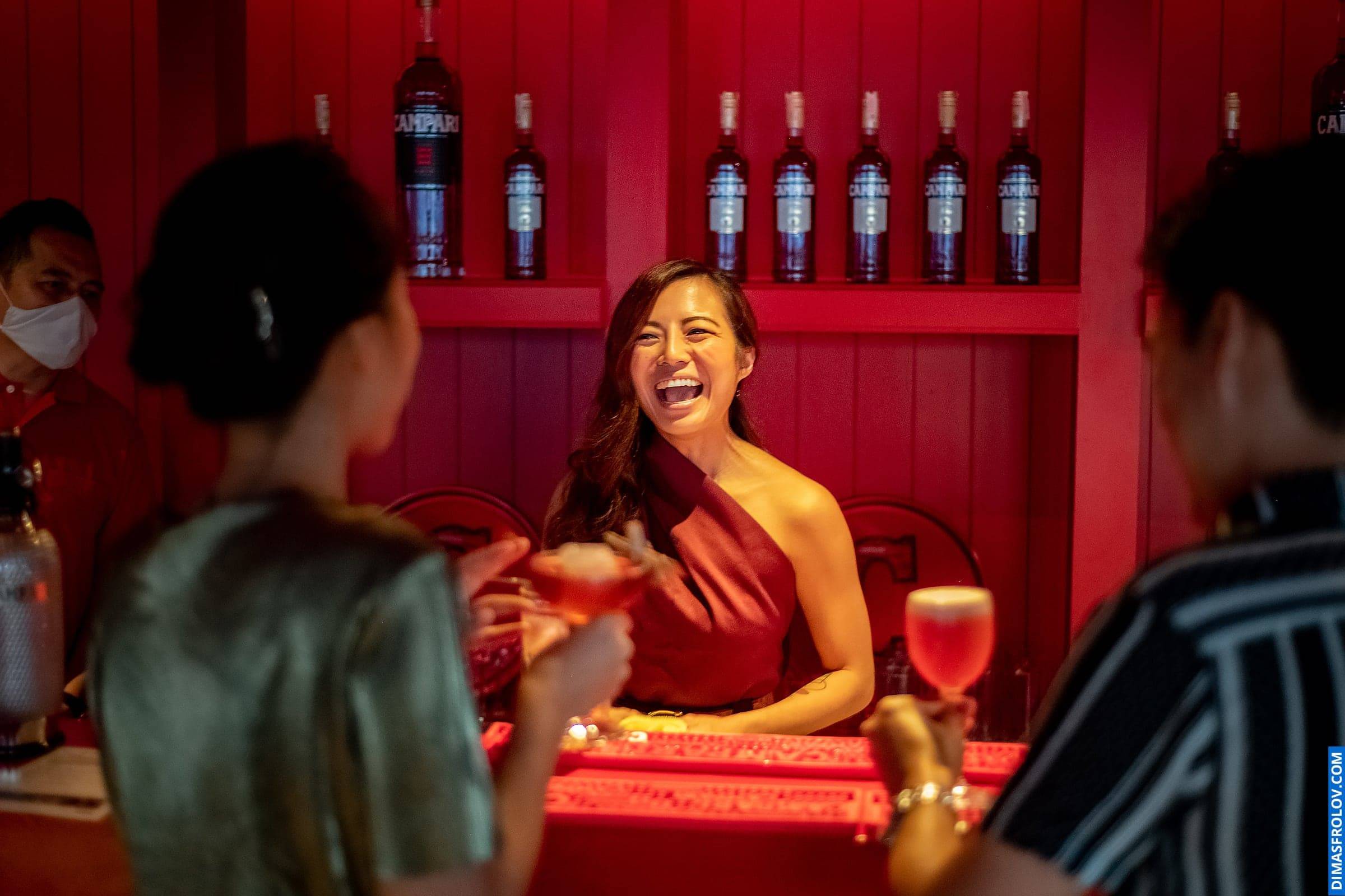 Joyful moment at bar — woman laughing and chatting with friends at event
