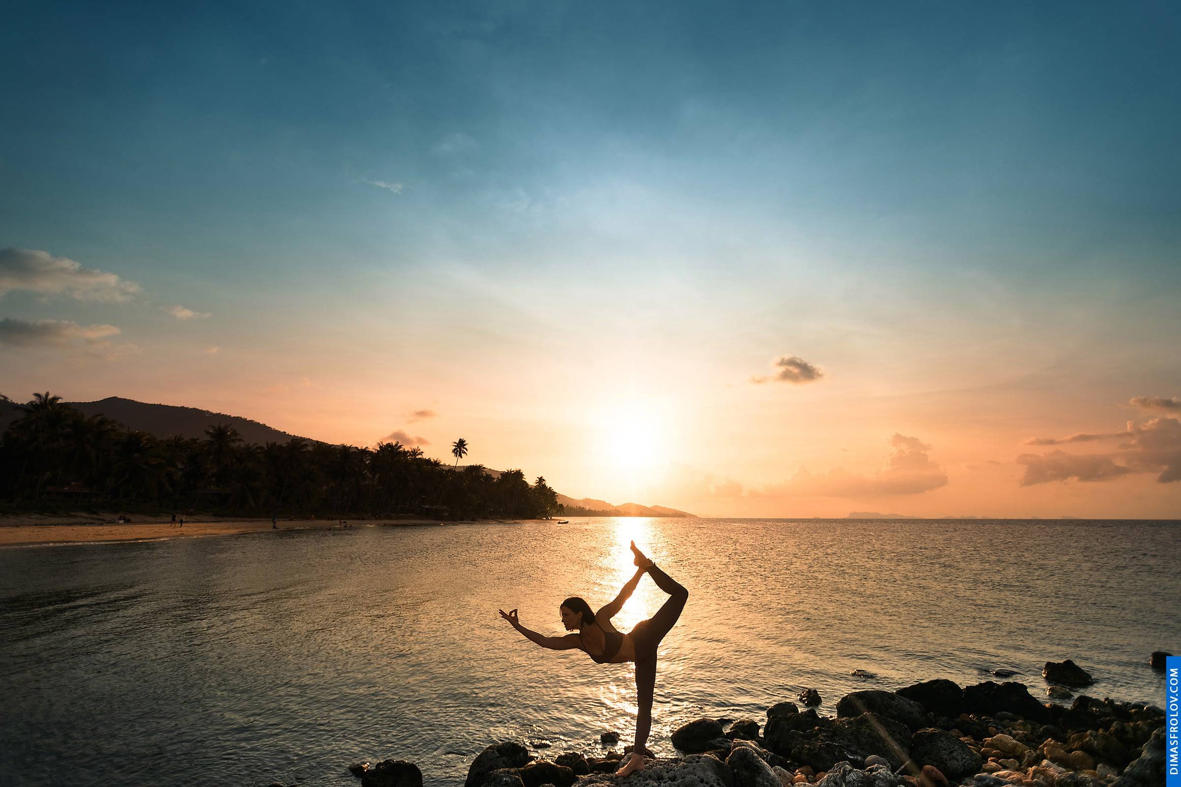 Silhouette of a woman in a graceful yoga pose at sunset by the sea
