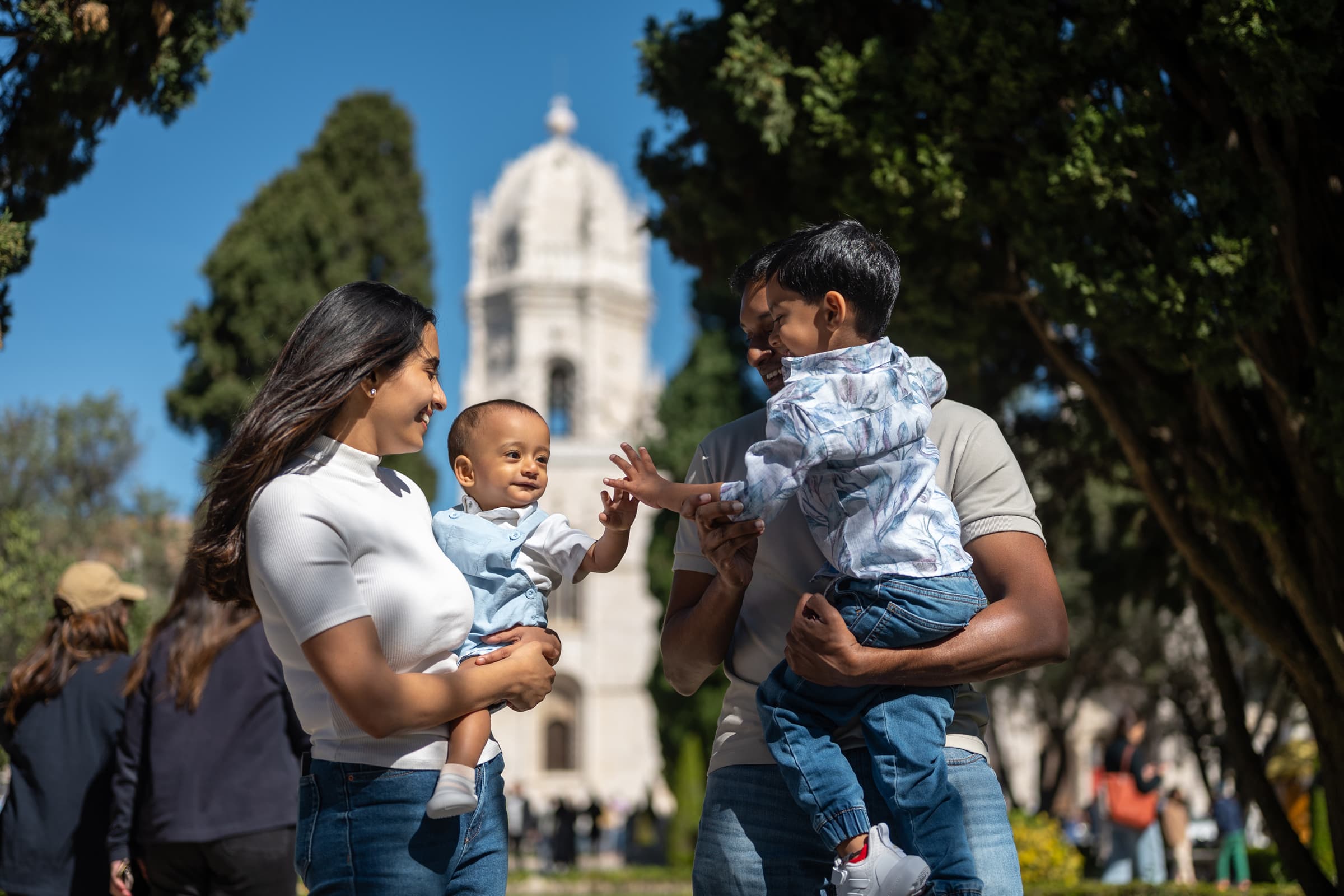 Parents holding two small children in&nbsp;the&nbsp;gardens by&nbsp;the&nbsp;Jeronimos Monastery, family photoshoot in&nbsp;Belem, Lisbon