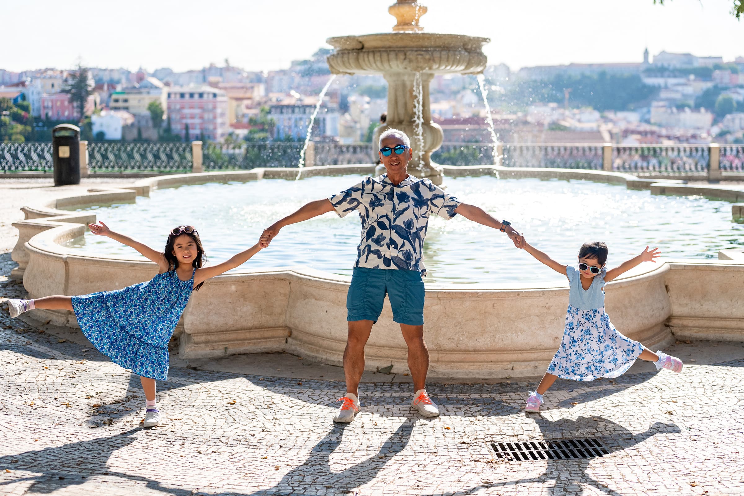 Grandfather and&nbsp;granddaughters at&nbsp;the&nbsp;fountain on&nbsp;the&nbsp;terrace of&nbsp;Miradouro de São Pedro de Alcântara. Mid-morning, and&nbsp;the&nbsp;shadows on&nbsp;the&nbsp;calçada show exactly how hard the&nbsp;light gets here.