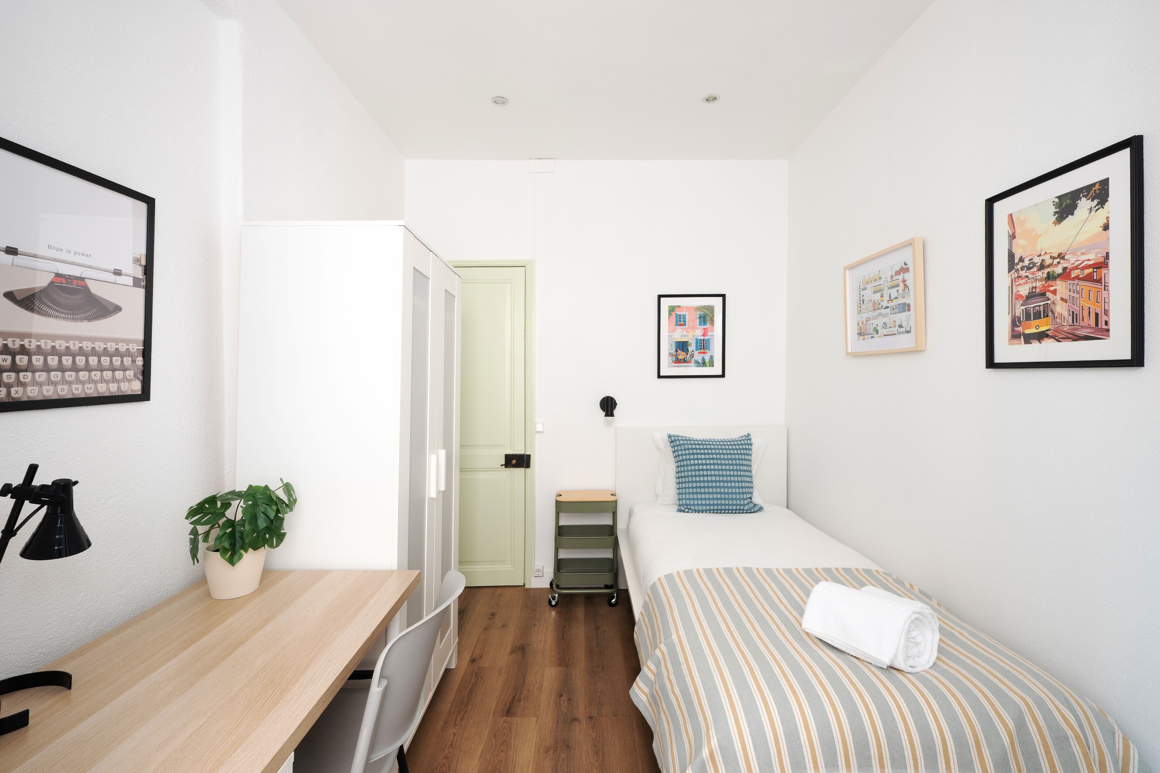 A small bright bedroom in a Lisbon flat, seen from the doorway
