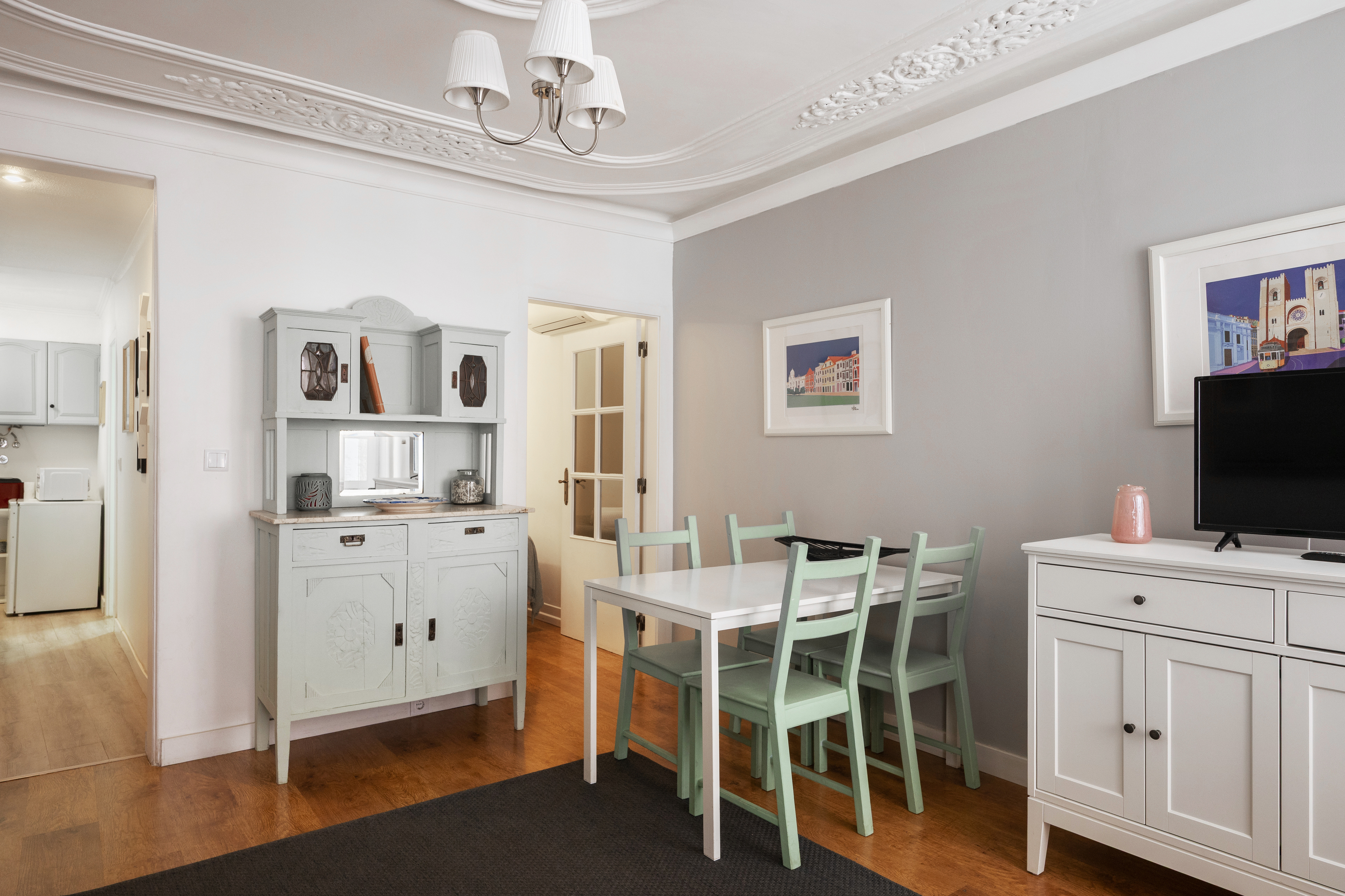 A dining area in a Lisbon flat with a moulded ceiling and a doorway through to the hall