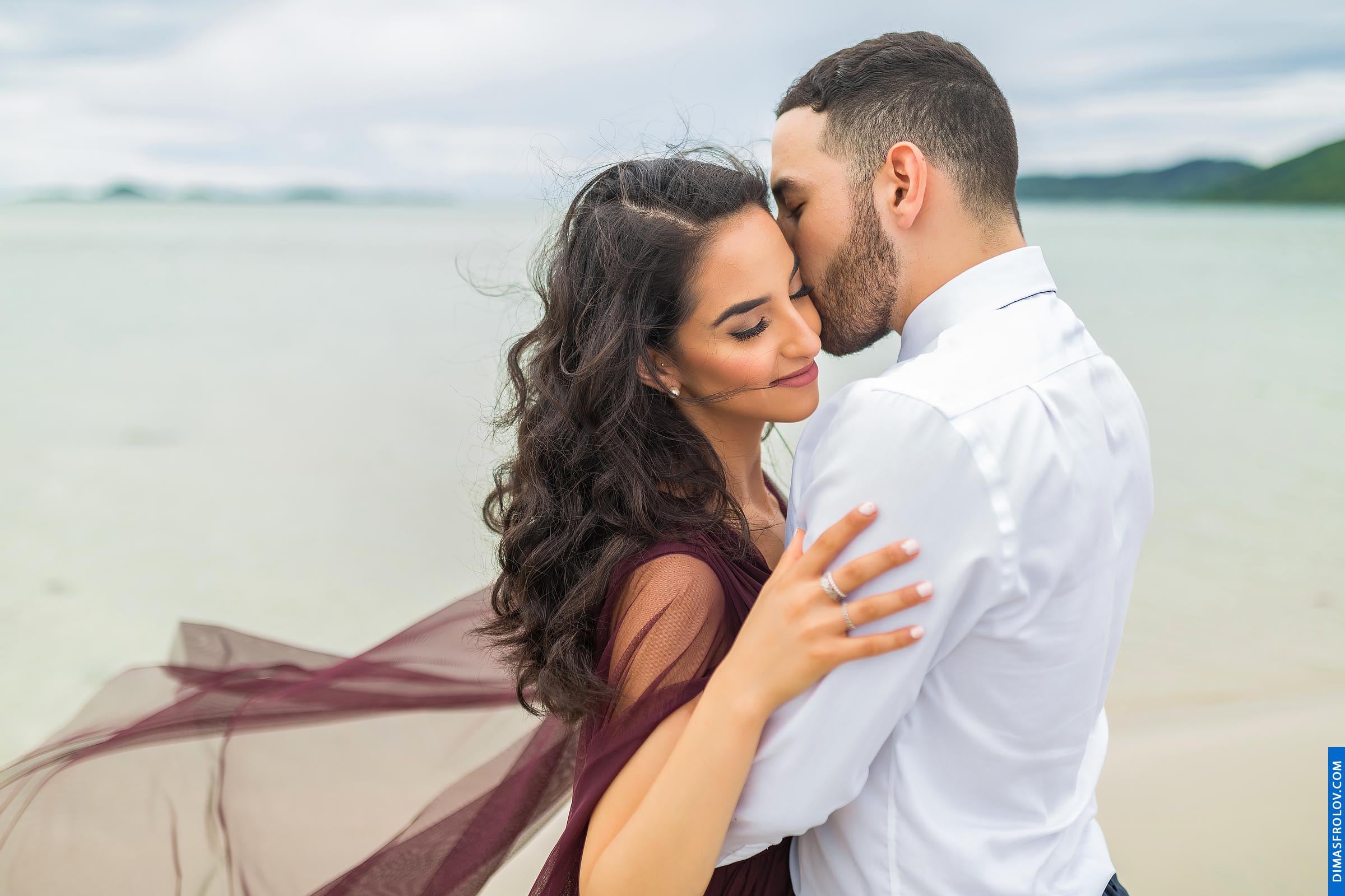 Intimate couple portrait by the water with romantic wind-blown dress