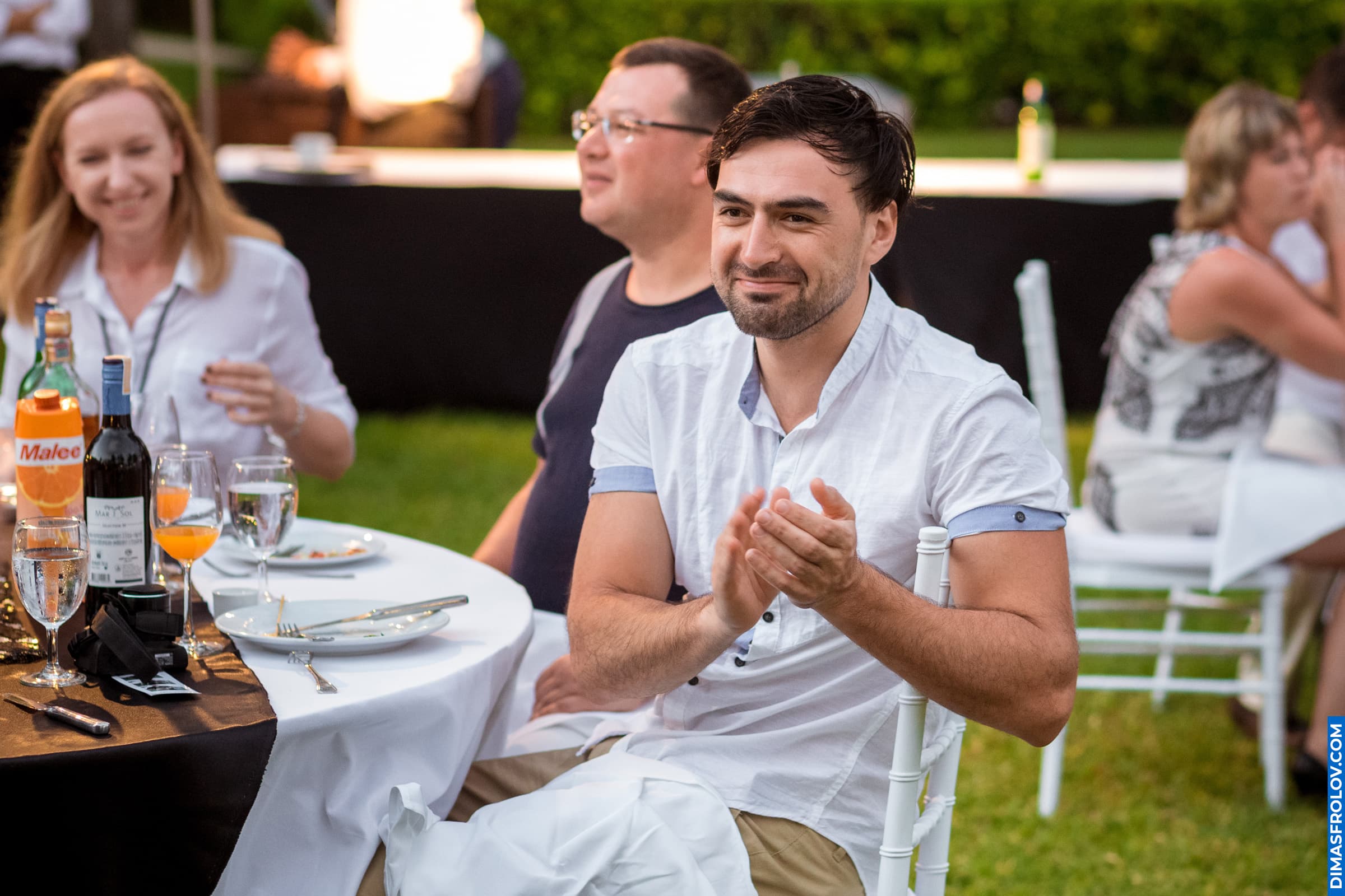 Outdoor dinner event — smiling guests enjoying evening with wine and conversation
