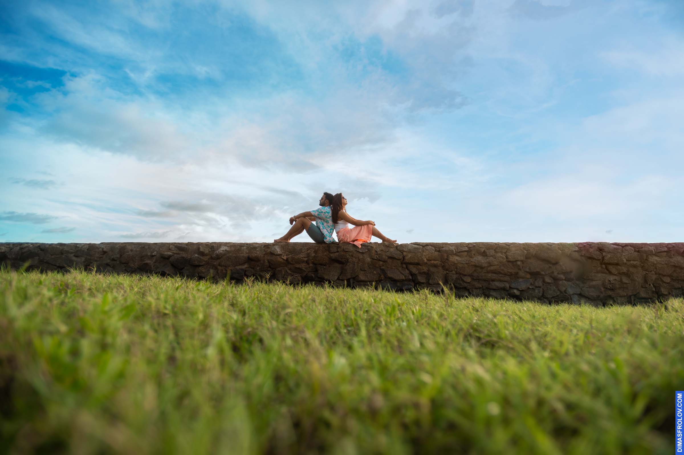 Romantic picnic scene with couple on a grassy hill under dramatic sky