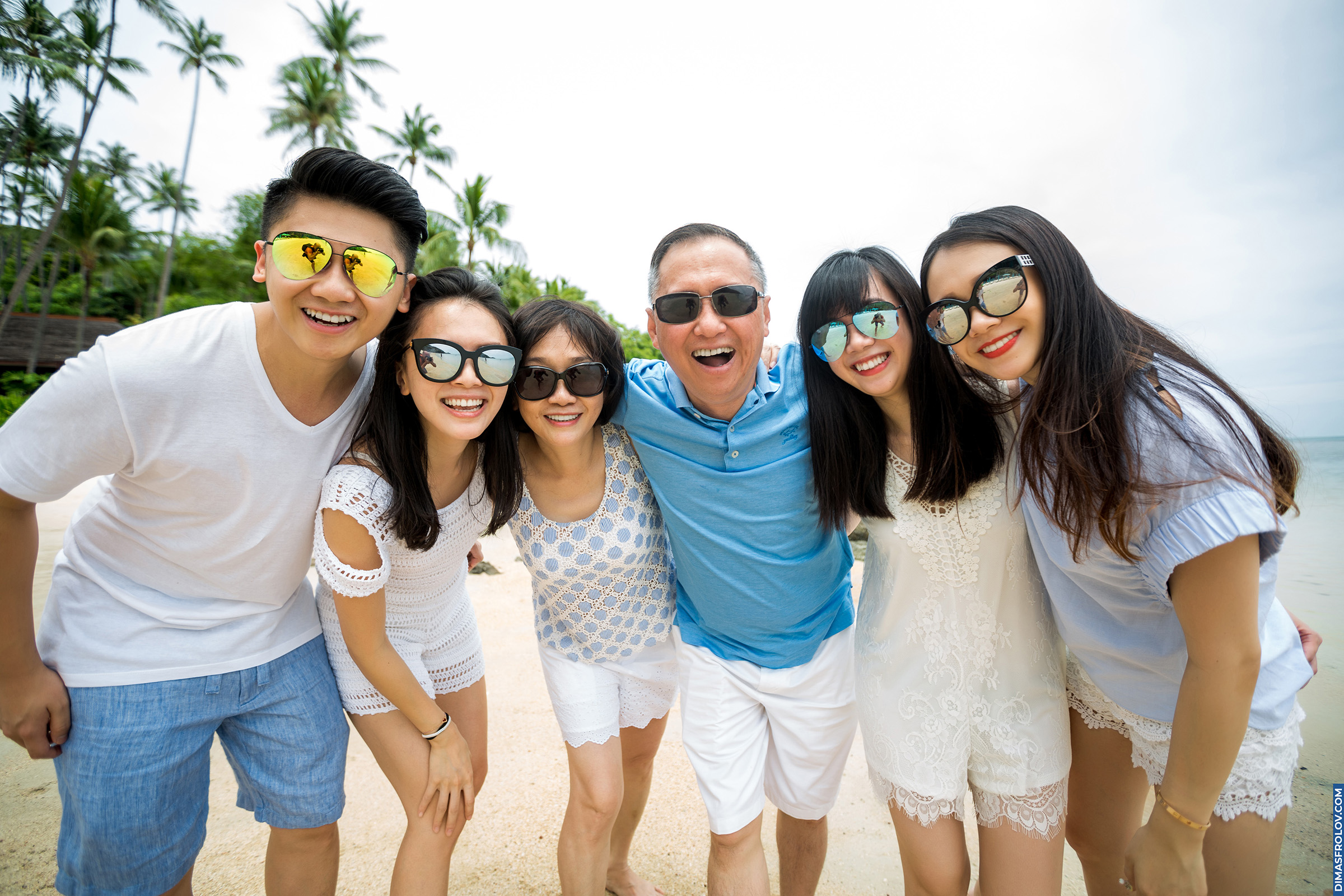 Família feliz e unida posando junta em uma praia tropical