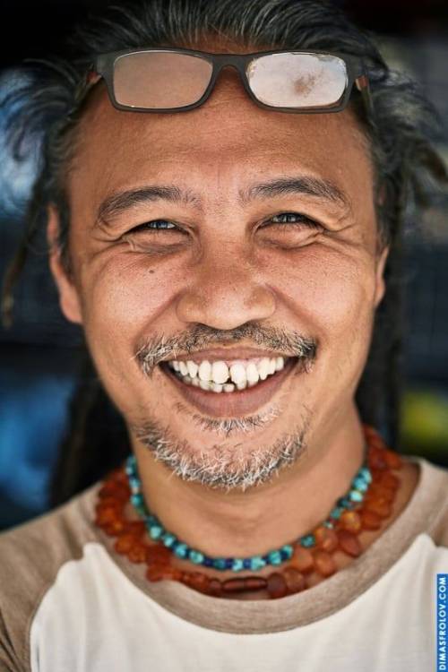 A cheerful street portrait: a smiling man with beads poses during a lively photo shoot