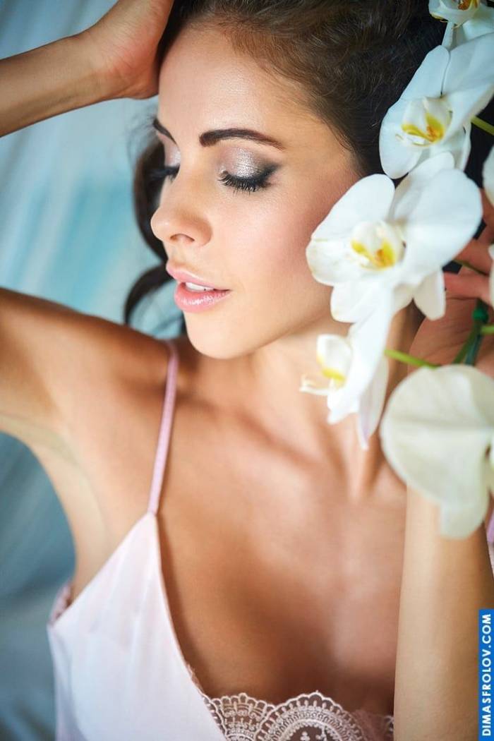 Um retrato floral de quarto: uma mulher em um vestido rosa adornado com orquídeas brancas durante uma delicada sessão de fotos