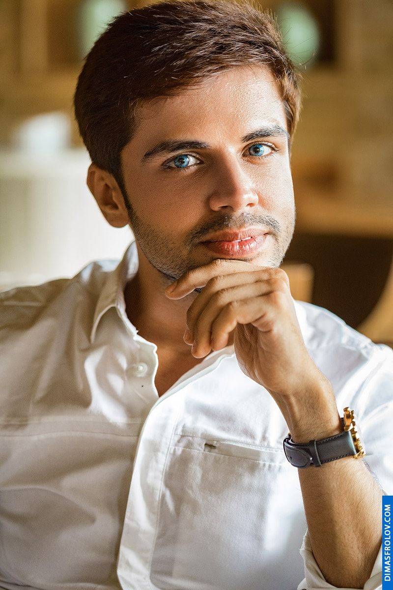 A thoughtful indoor portrait: a man in a white shirt poses with a hand on his chin during a calm photo session