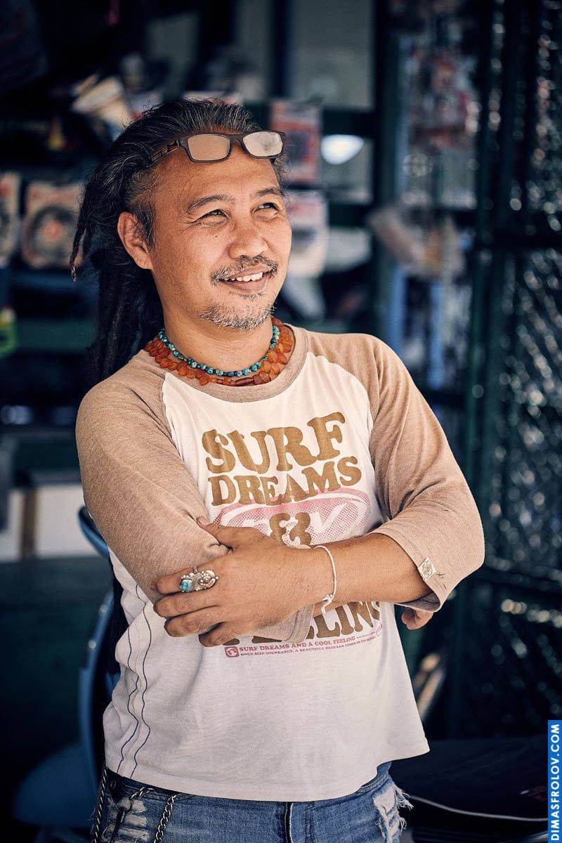 ภาพพอร์ตเทรตเขตร้อน: ผู้ชายในเสื้อเซิร์ฟยืนไขว้แขนระหว่างเซสชั่นถ่ายภาพที่ผ่อนคลาย