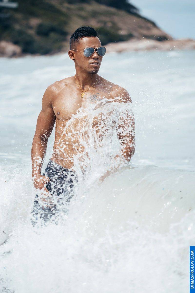A dynamic ocean photo shoot: a tattooed man splashes in waves during an energetic photo session